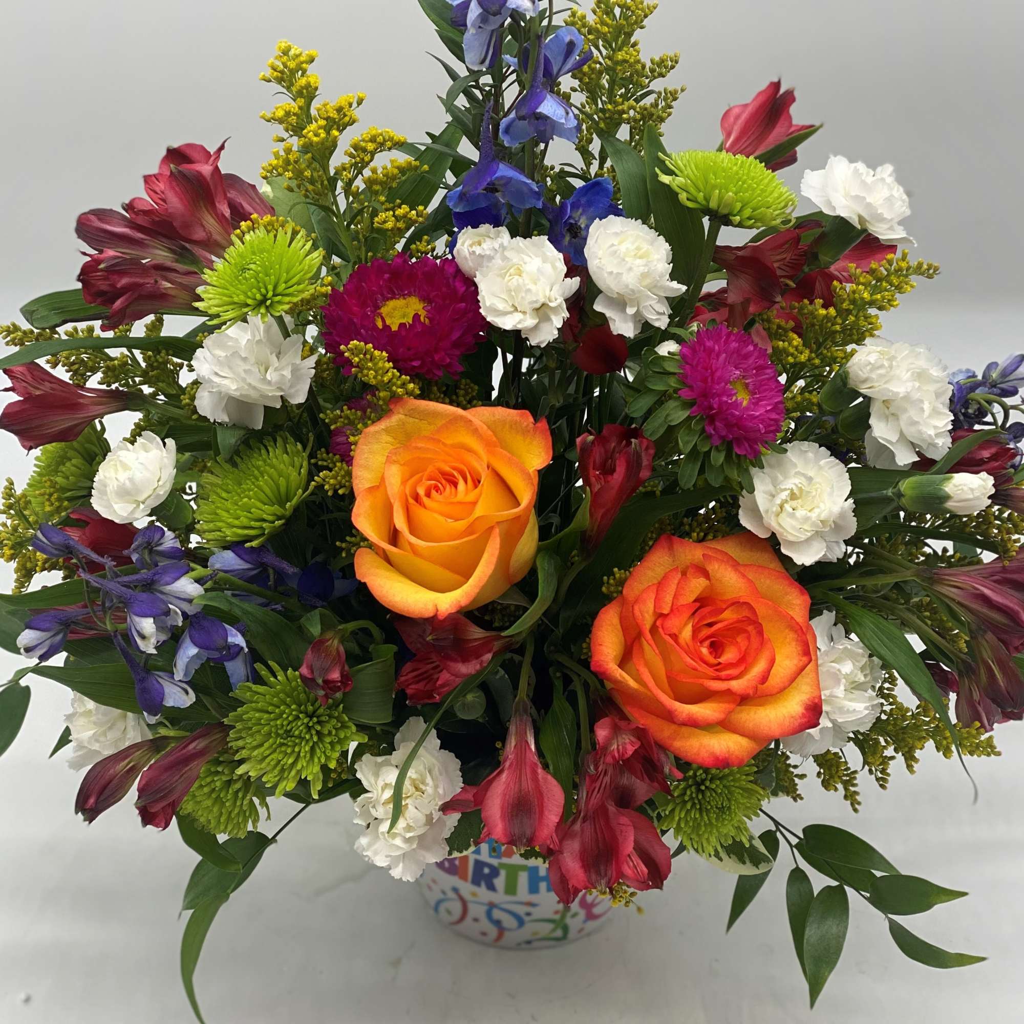 A bright mix of fresh cut flowers designed in a hard plastic