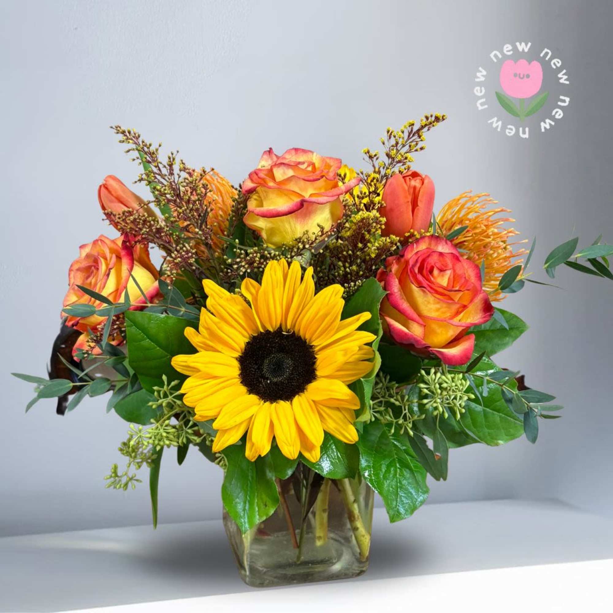 Bouquet of yellow sunflowers and orange roses in a glass vase