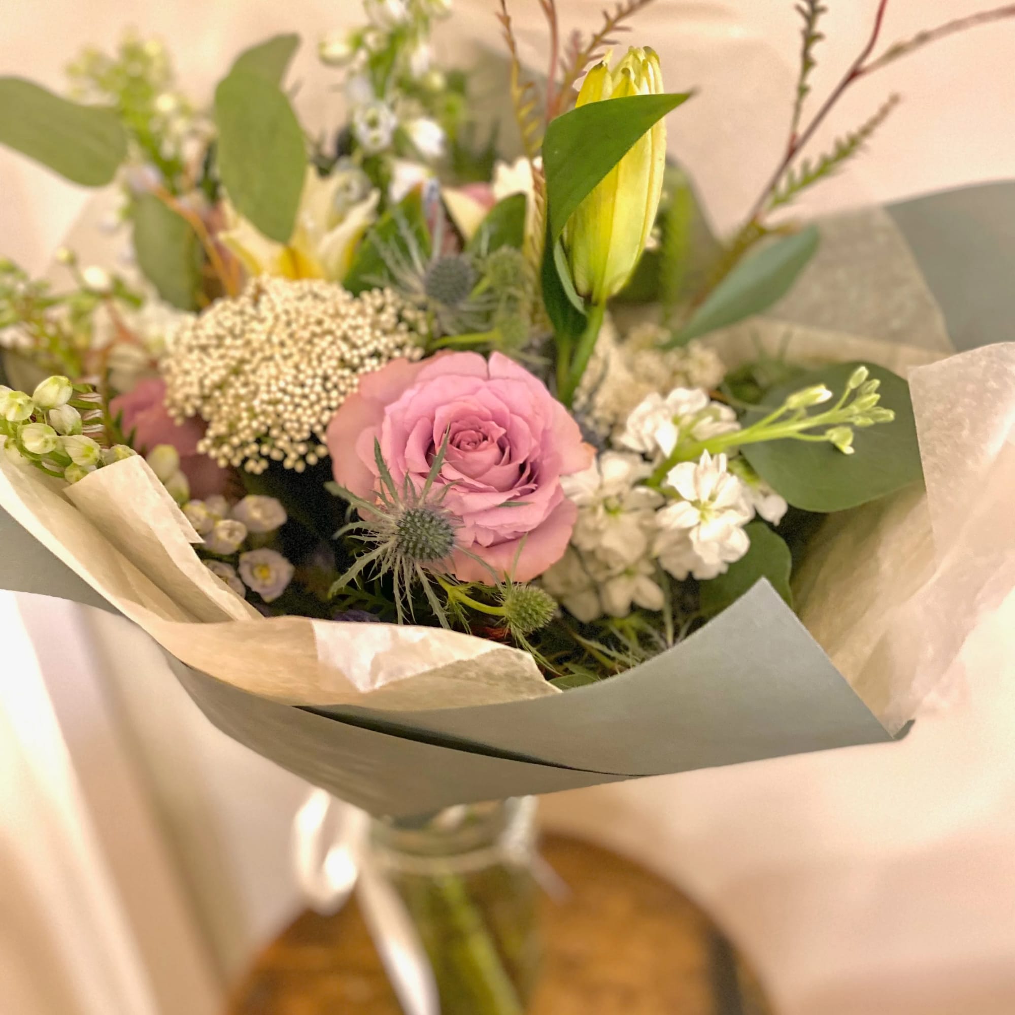 Bouquet with a pink rose, yellow lily buds, and white filler flowers