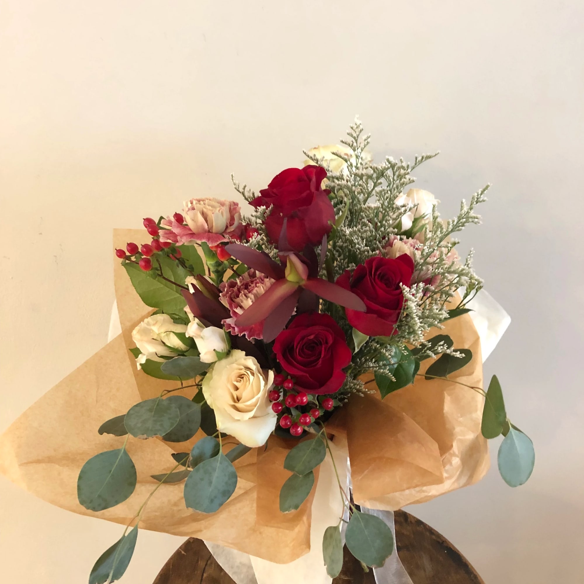 Bouquet of red and cream roses with pink accents wrapped in brown paper