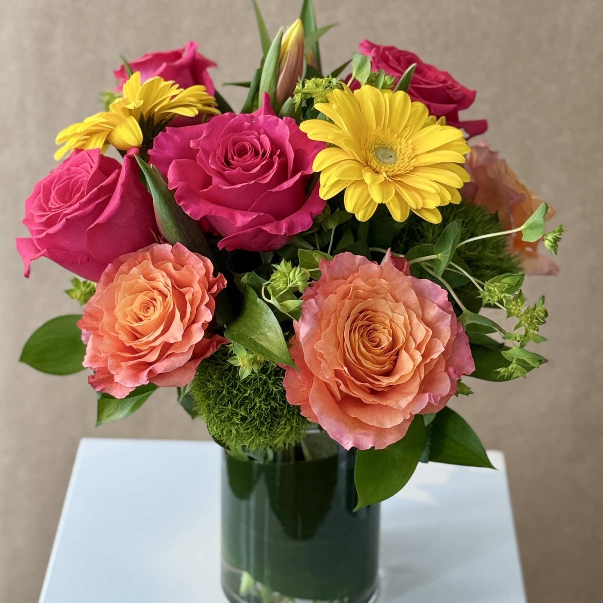 Bouquet of pink and peach roses with yellow daisies in a glass vase