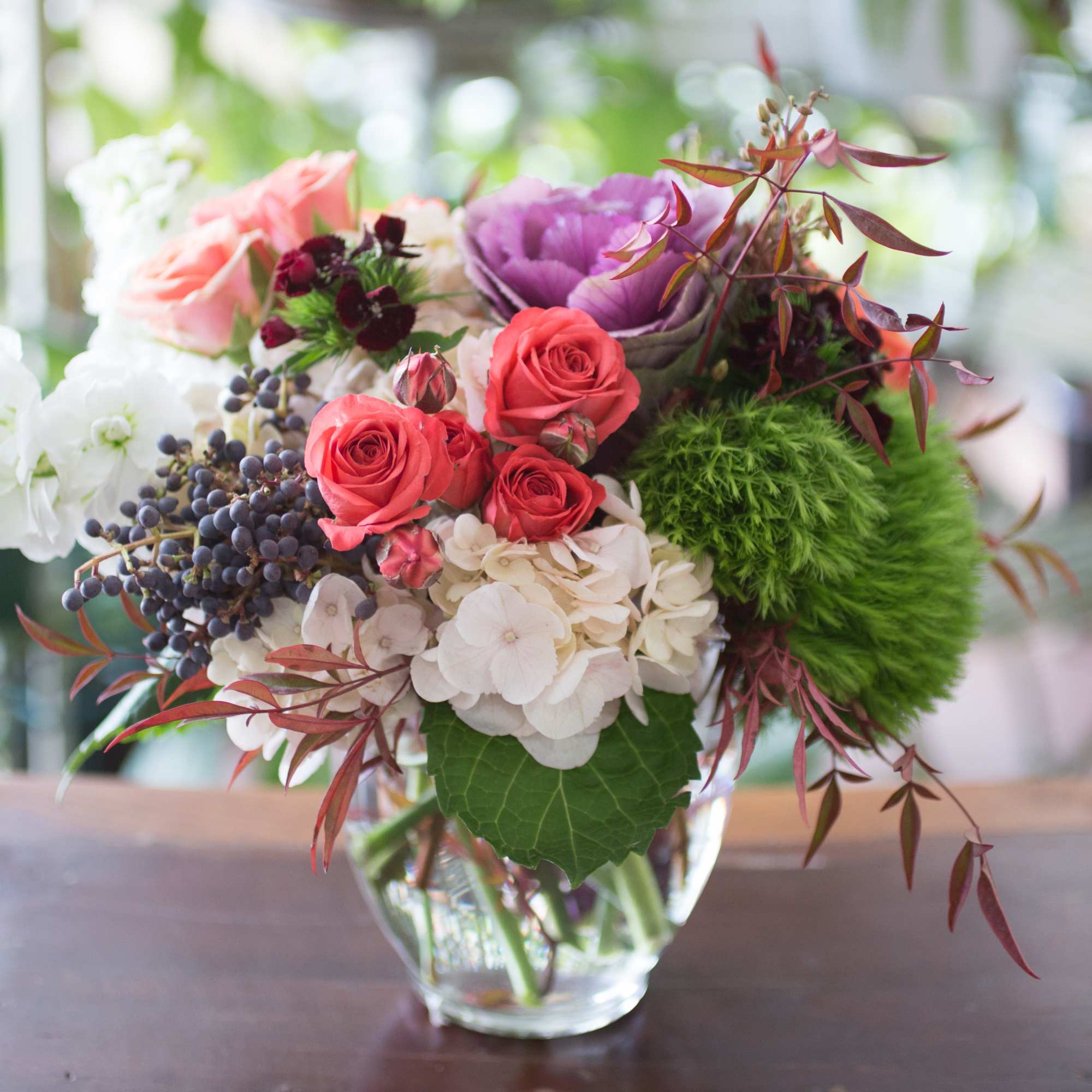 Mixed bouquet of roses, hydrangea, and greenery in a glass vase