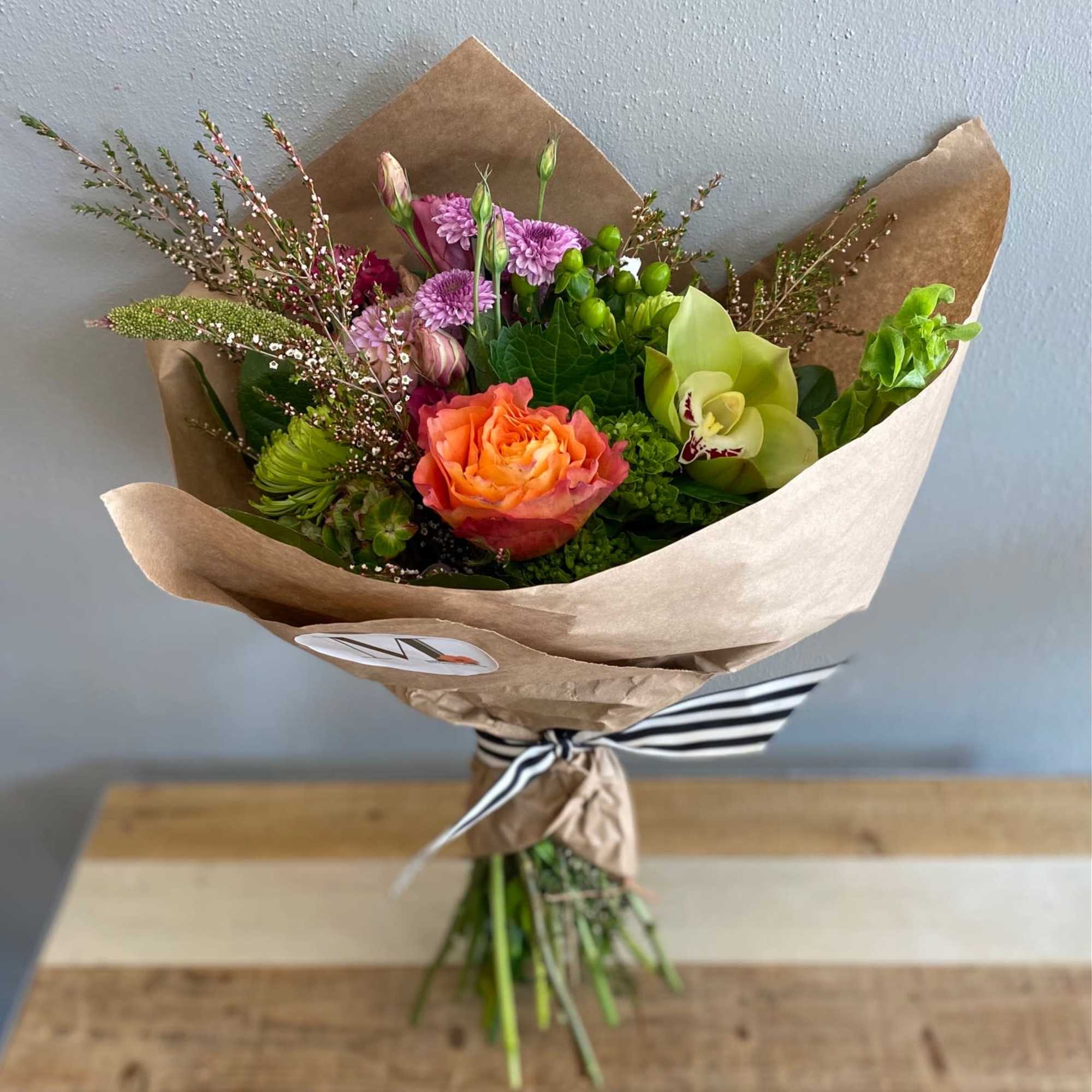 Bouquet of orange and purple flowers wrapped in brown paper
