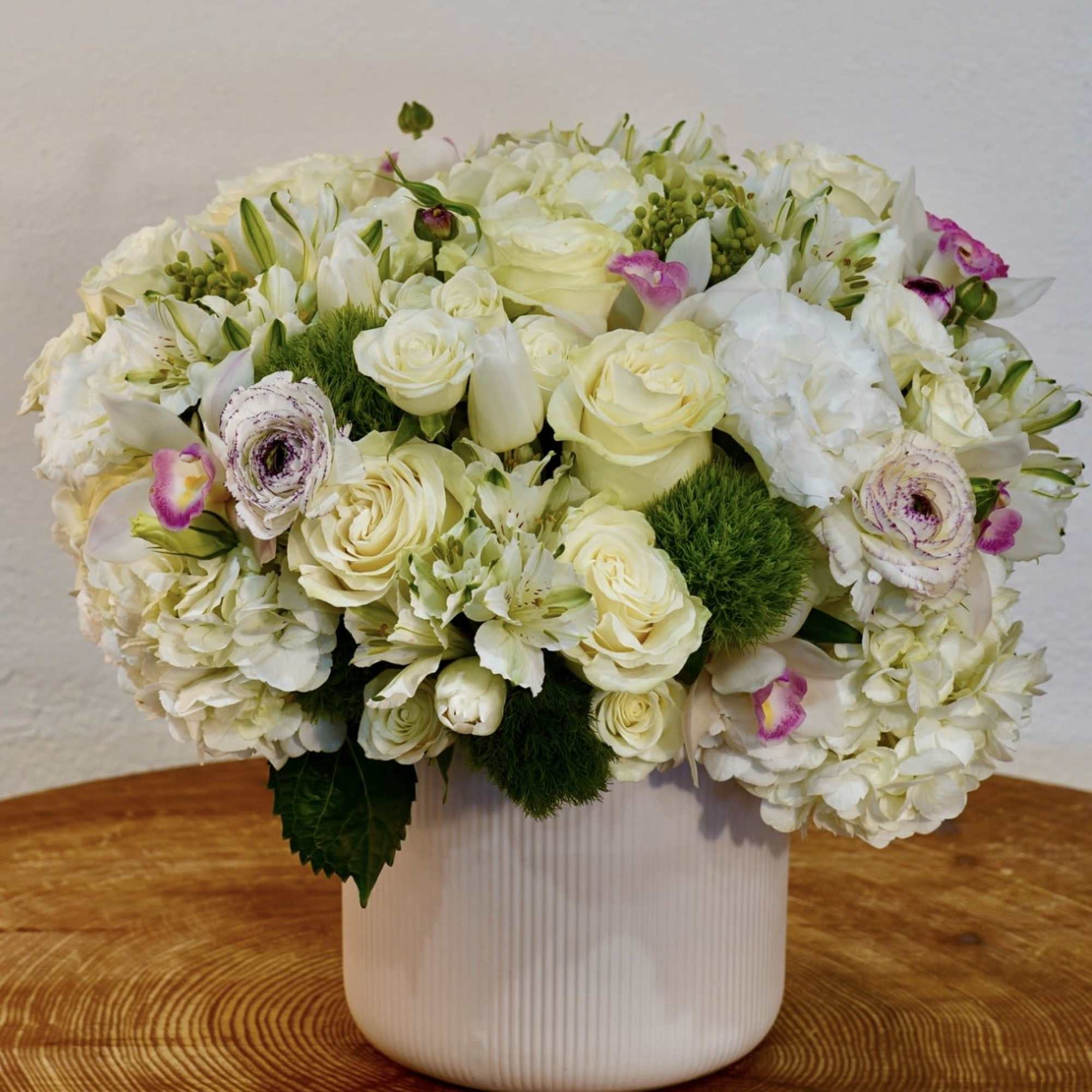 A beautiful and elegant white garden-style floral arrangement featuring hydrangea, roses, and