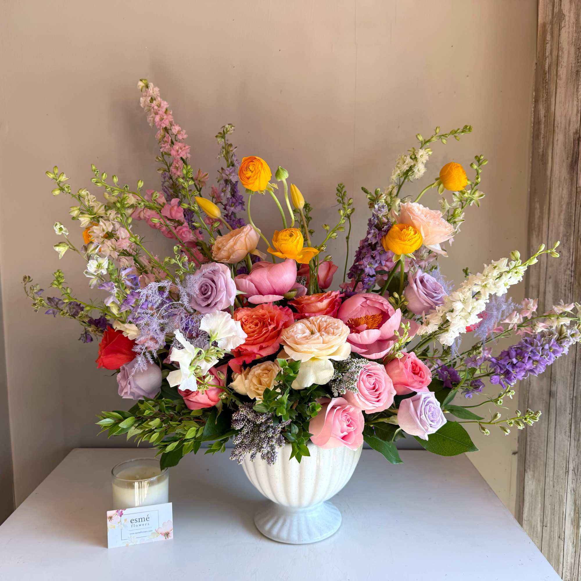 Colorful mixed flower arrangement in a white pedestal vase