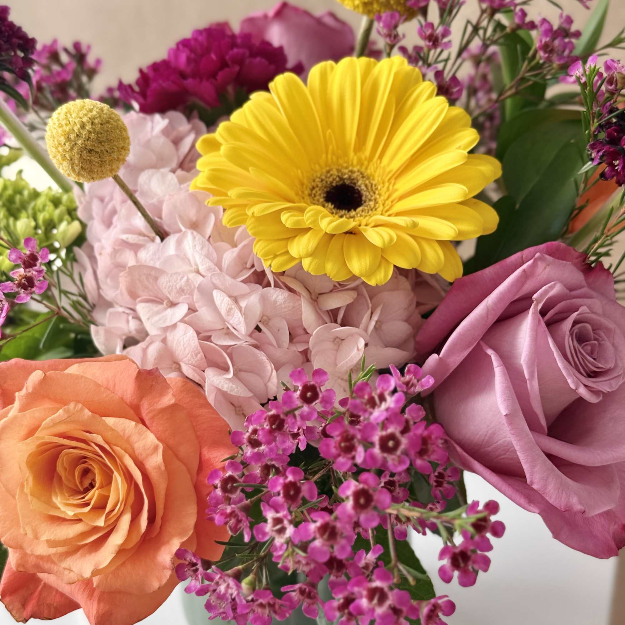 Mixed bouquet with roses, hydrangea, and a yellow gerbera daisy in a glass vase