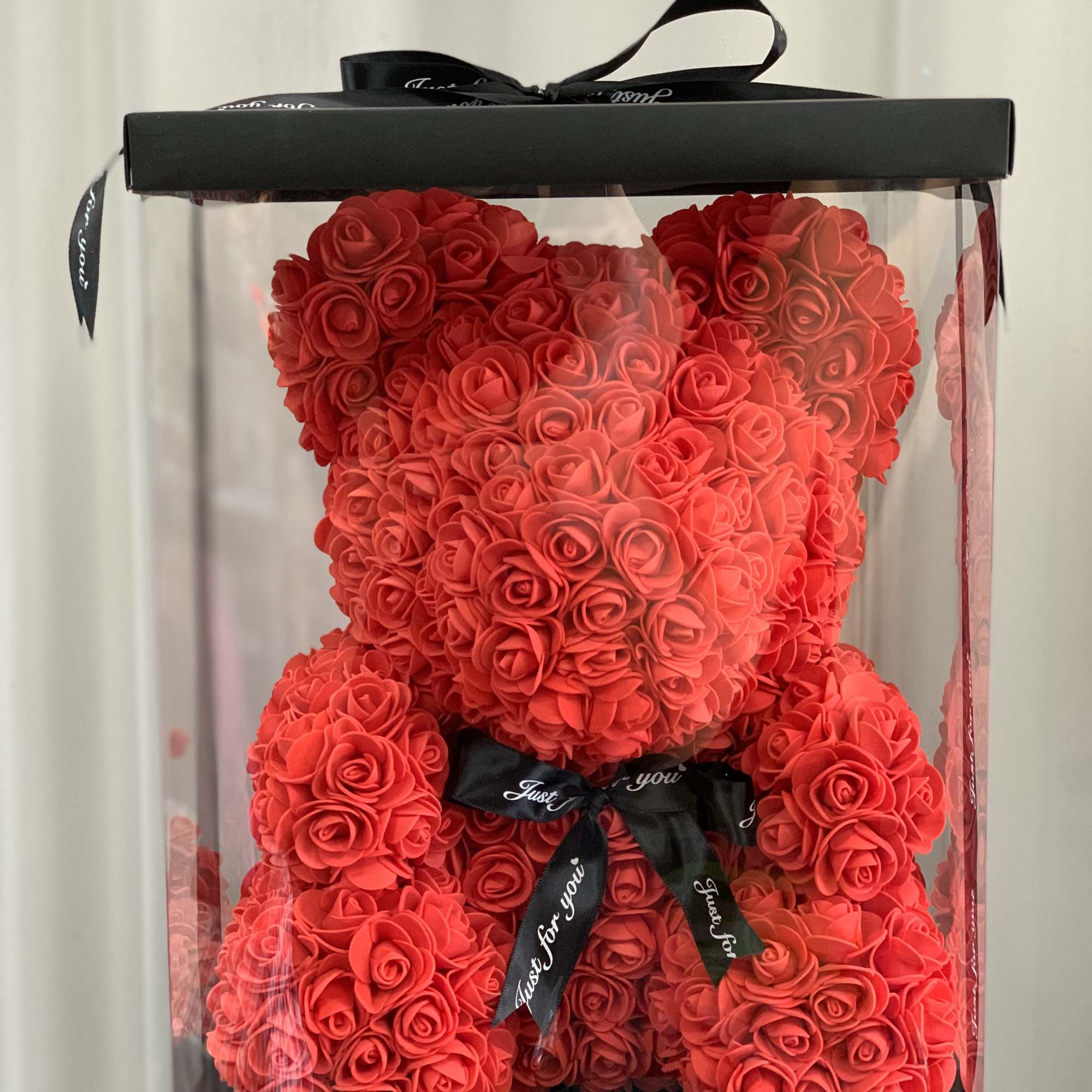 Red rose teddy bear in a clear gift box with a black ribbon