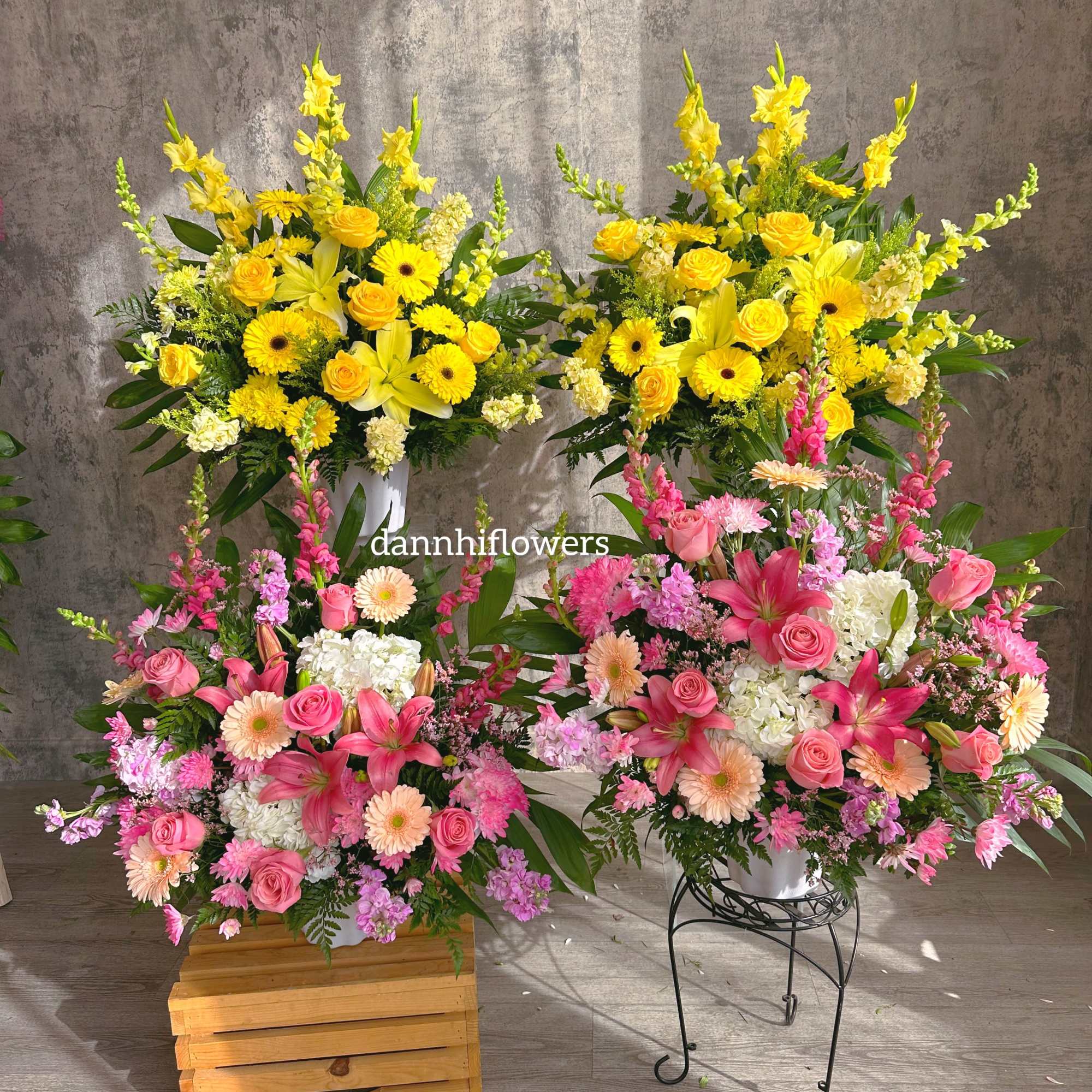 Two large floral arrangements with yellow and pink blooms in white containers