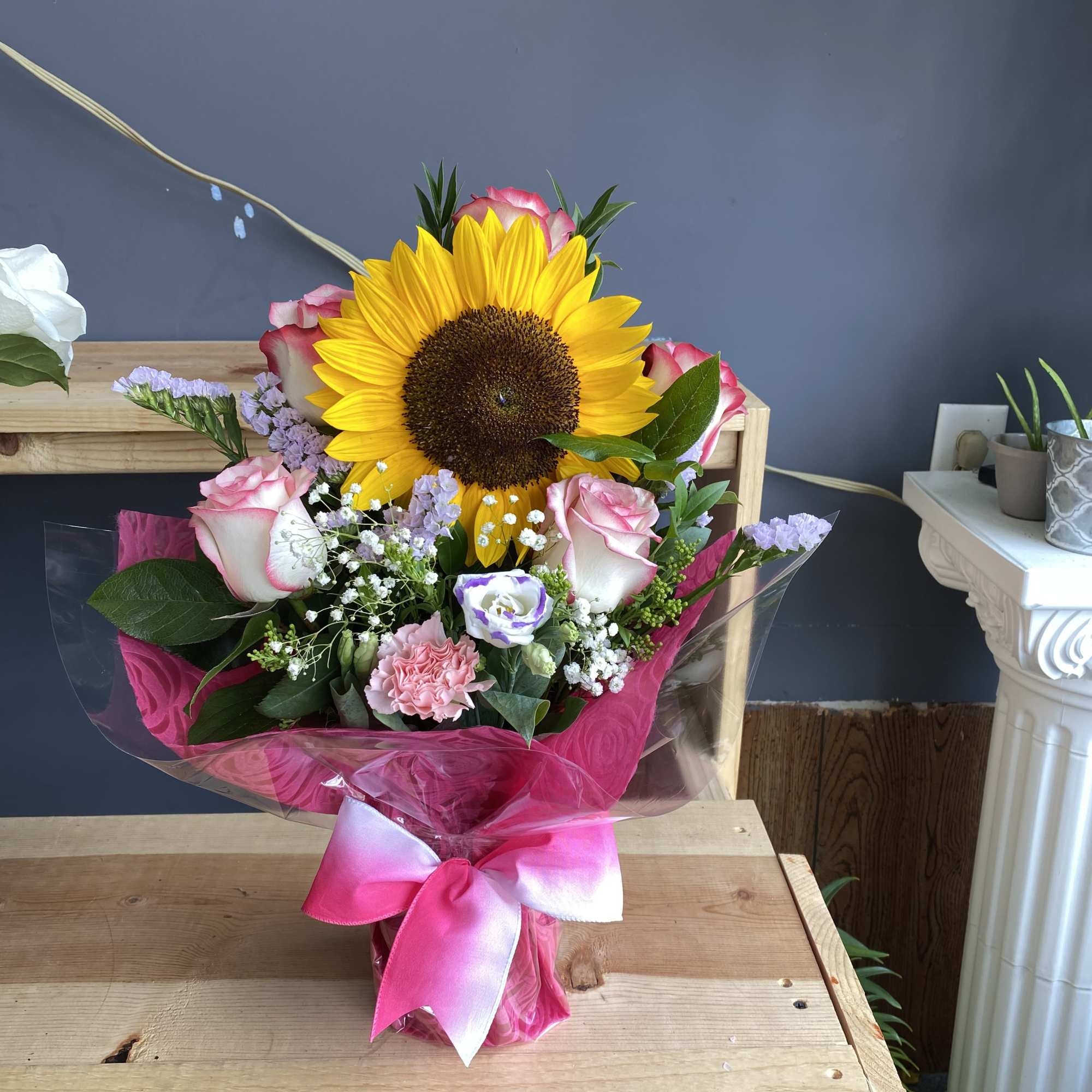 Bouquet with a sunflower, pink roses, and a pink ribbon wrap