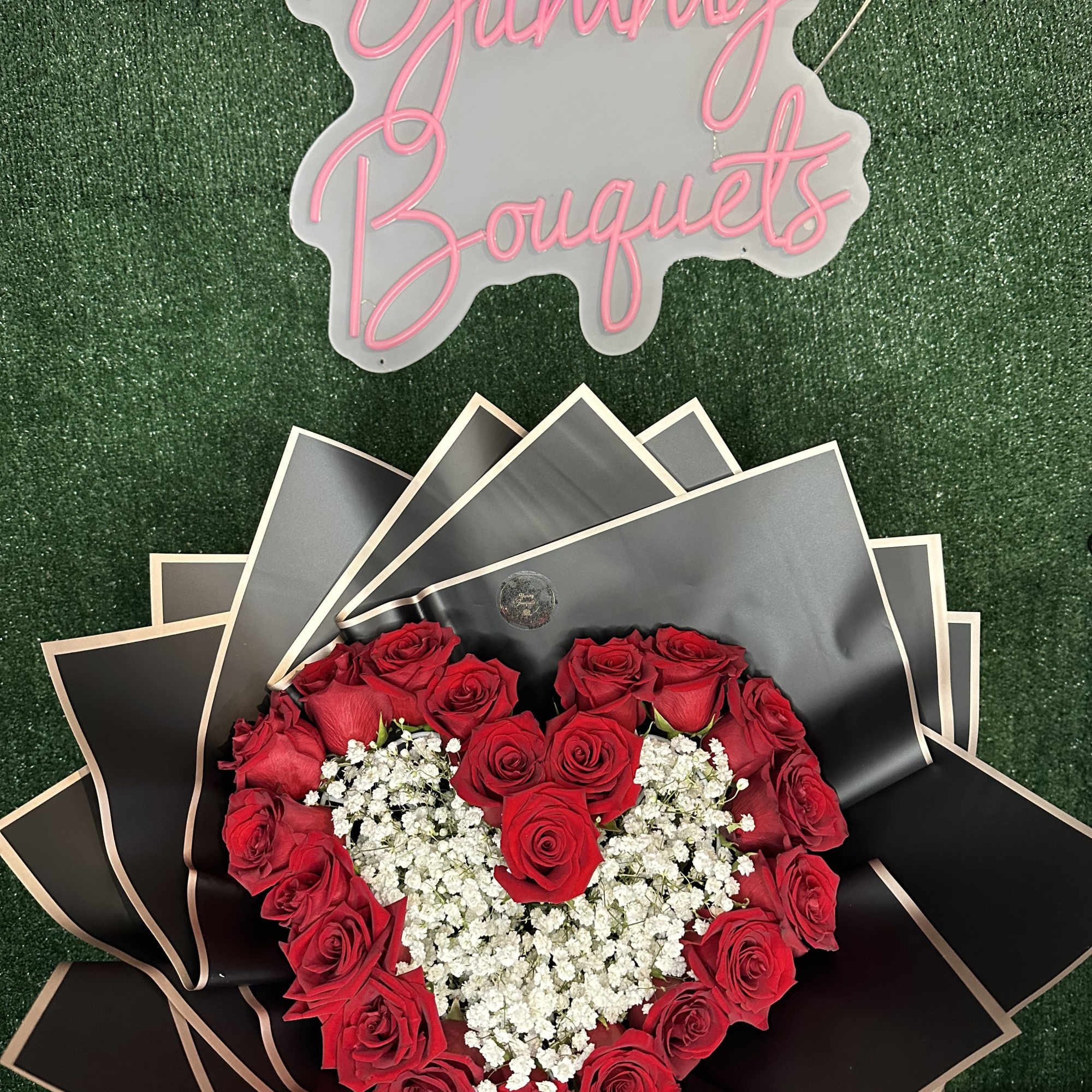 Heart-shaped red rose bouquet with white baby's breath and black wrapping