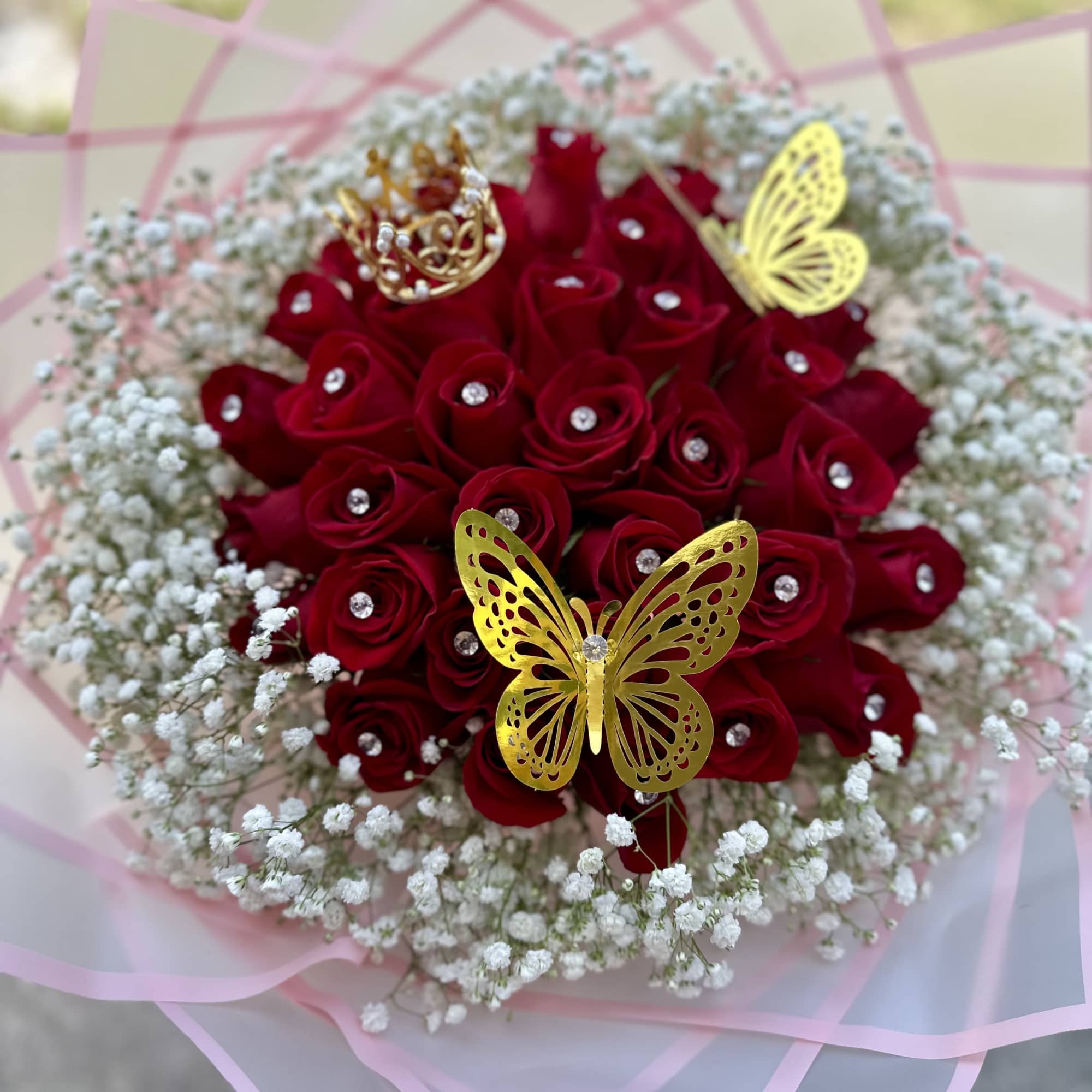 Red rose bouquet with baby’s breath, gold butterfly picks, and a pink wrap