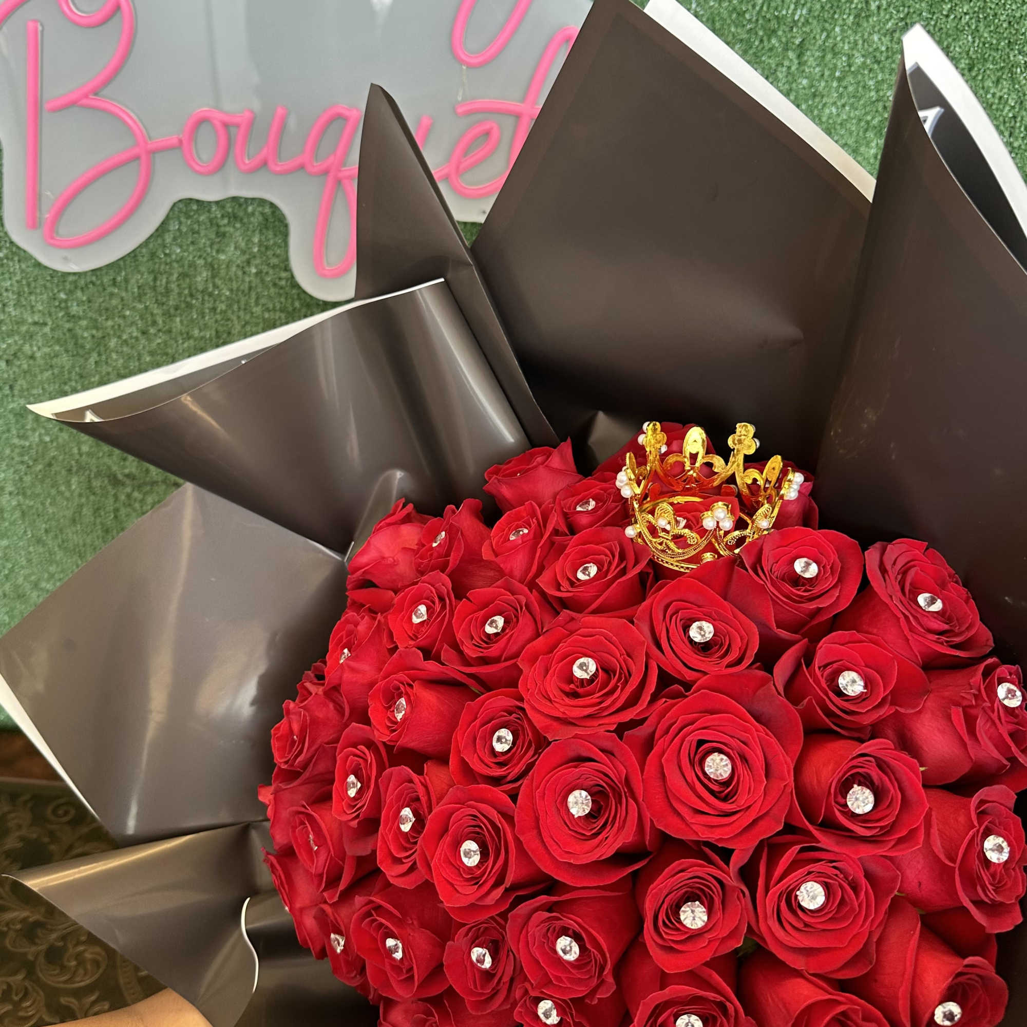 Bouquet of red roses wrapped in dark paper with a small gold crown