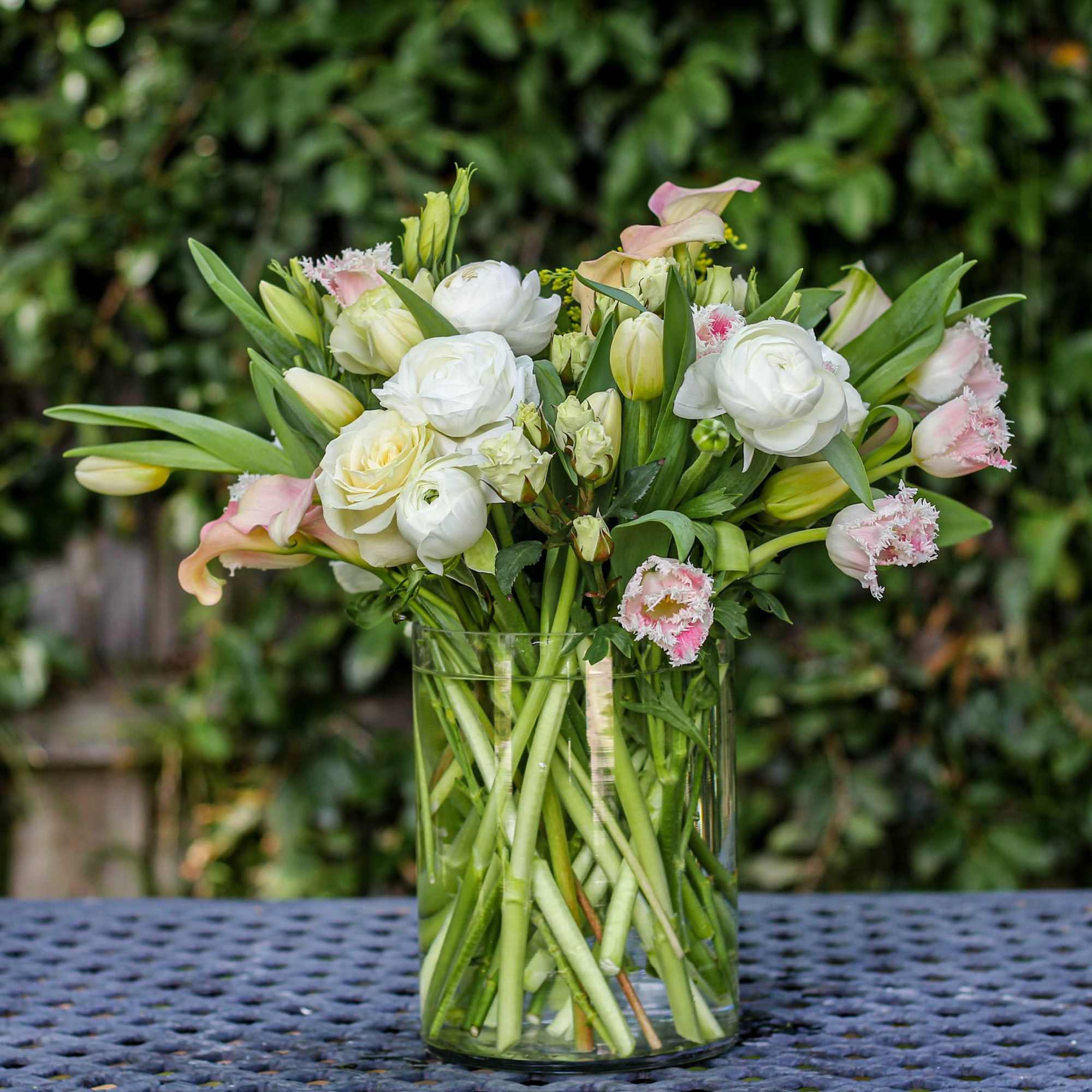 White and pale pink flowers arranged in a clear glass vase