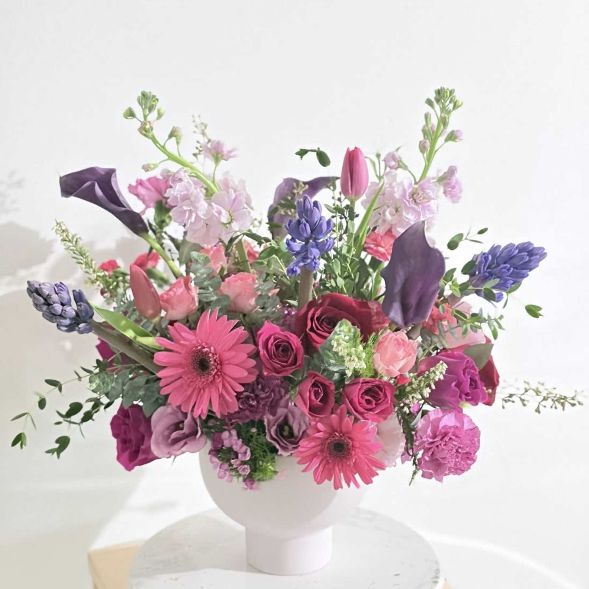 Pink and purple mixed bouquet in a white vase
