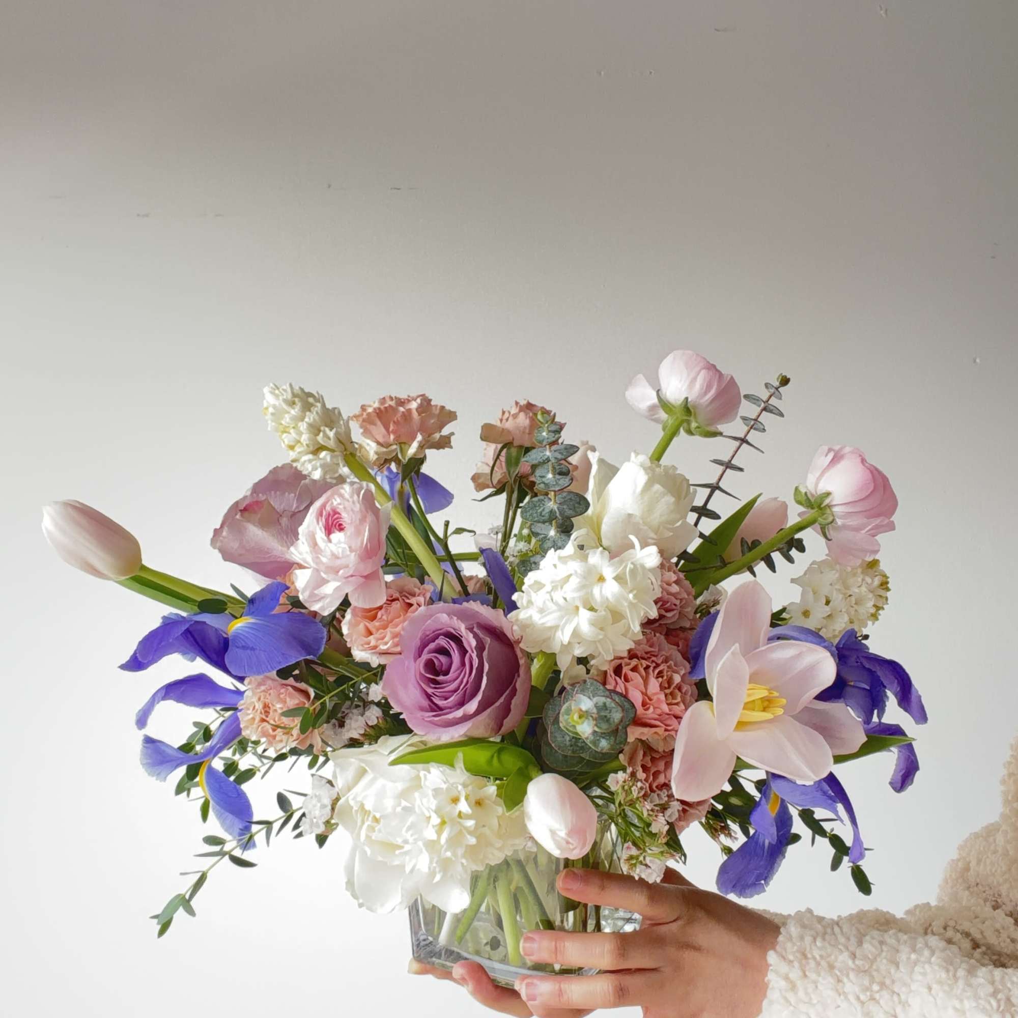 Handheld bouquet of pink, white, and purple flowers in a glass vase