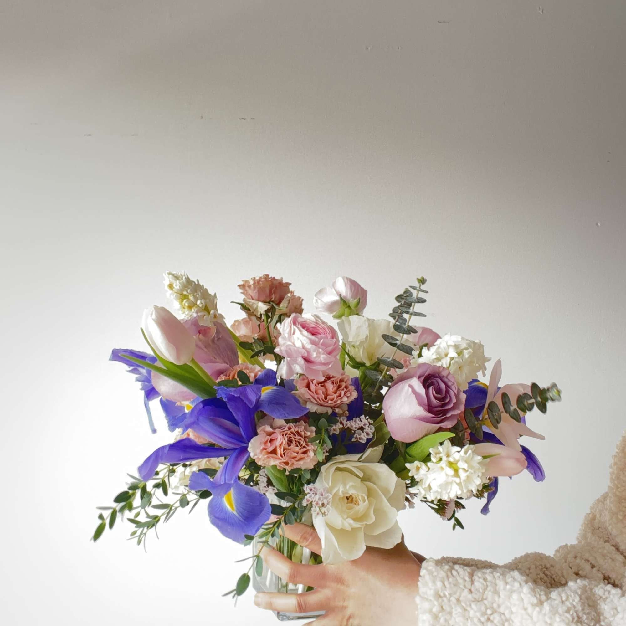 Mixed bouquet of pink, white, and purple flowers in a glass vase