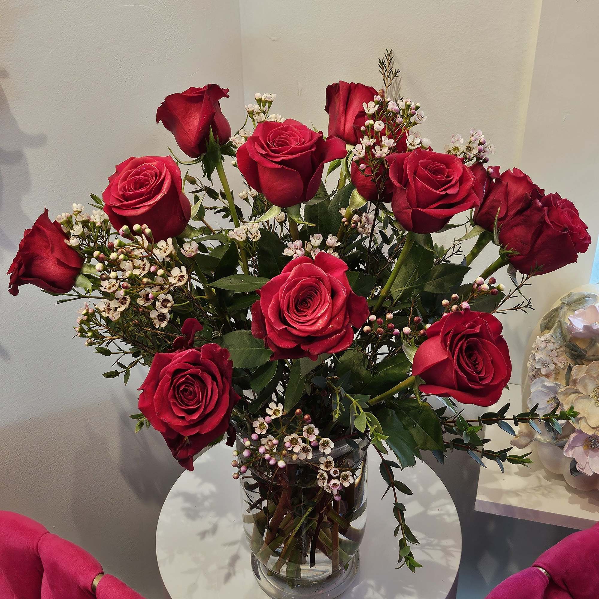 Red roses arranged in a clear glass vase with small white filler flowers