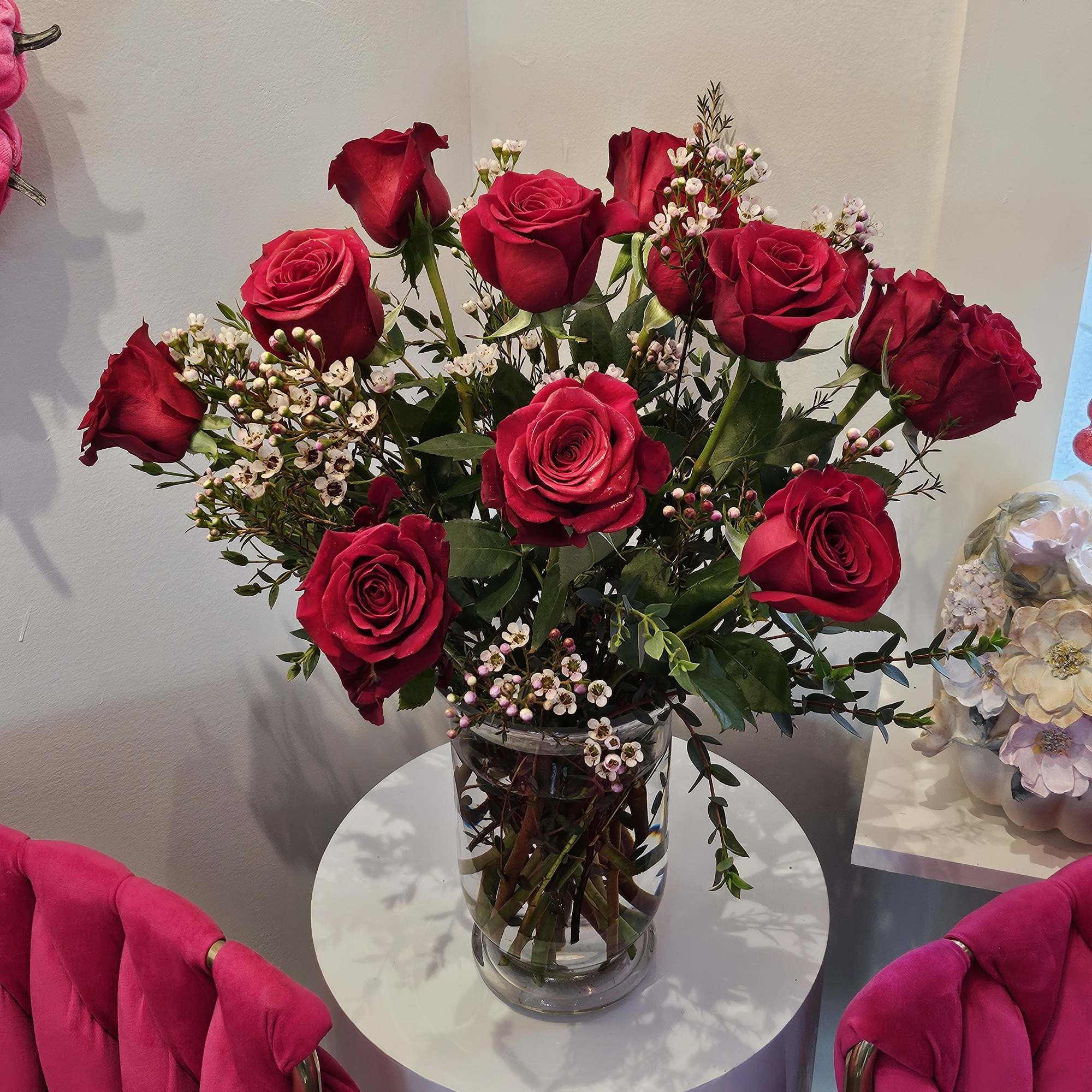 Red roses arranged in a clear glass vase with small white filler flowers.