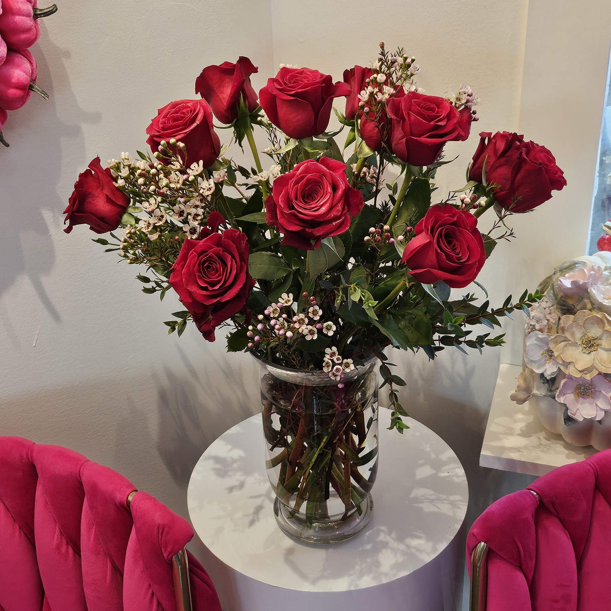 Red roses arranged in a clear glass vase on a small round table