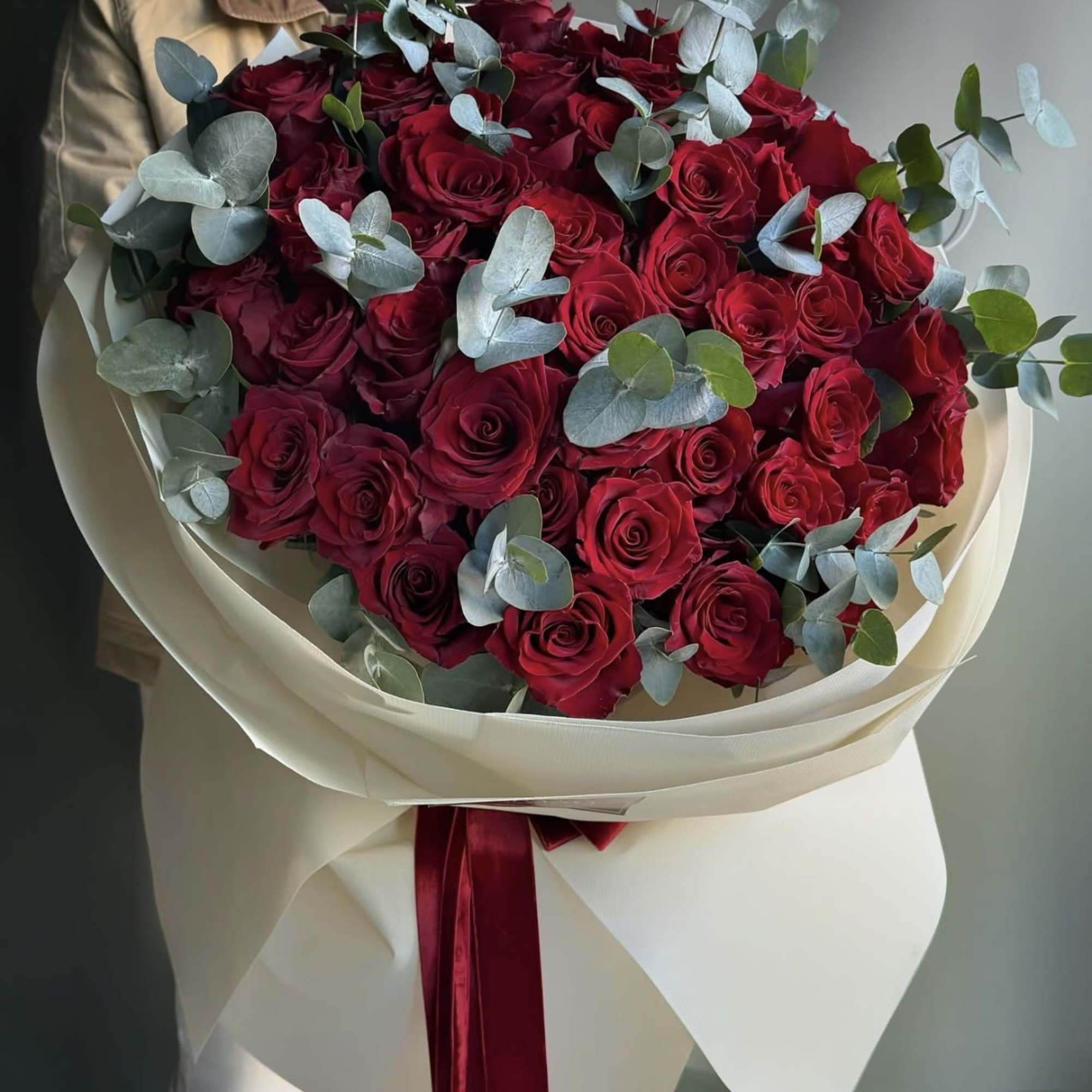 Bouquet of red roses with eucalyptus in cream wrapping