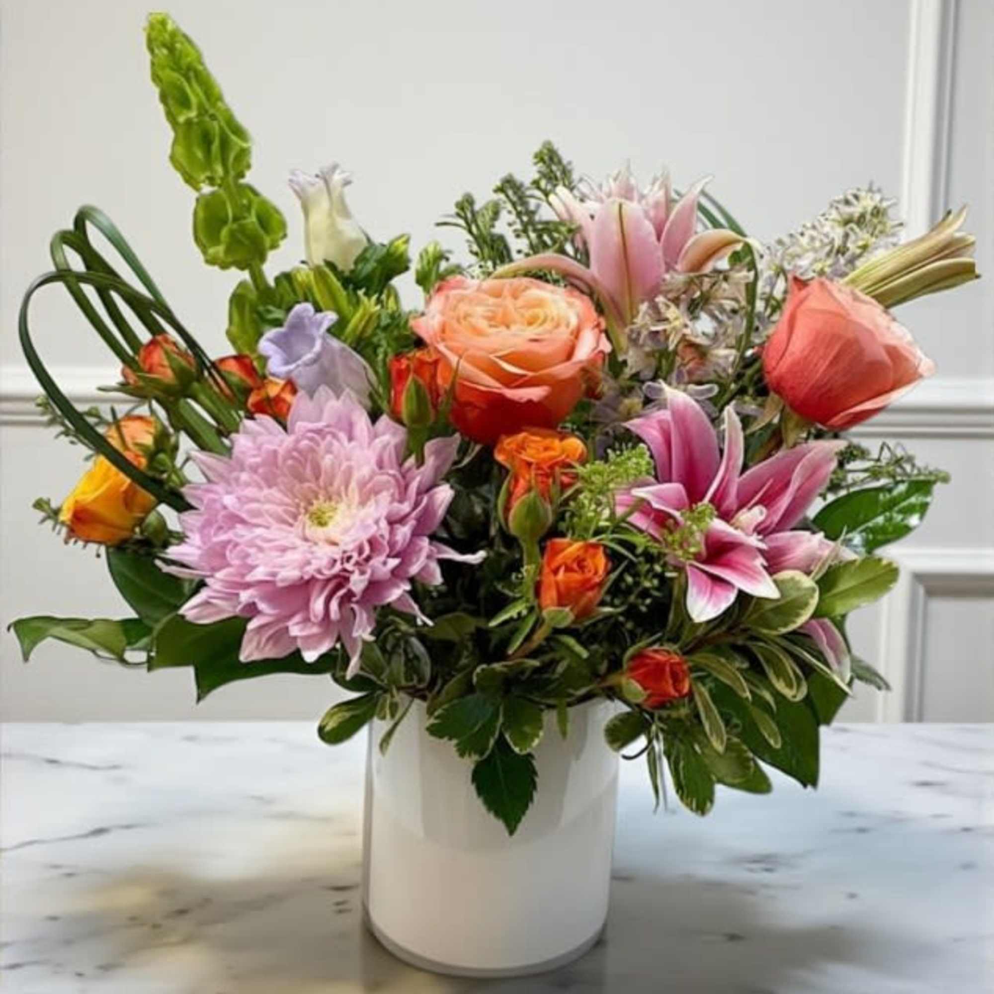 Mixed bouquet in a white vase with pink, peach, and purple flowers