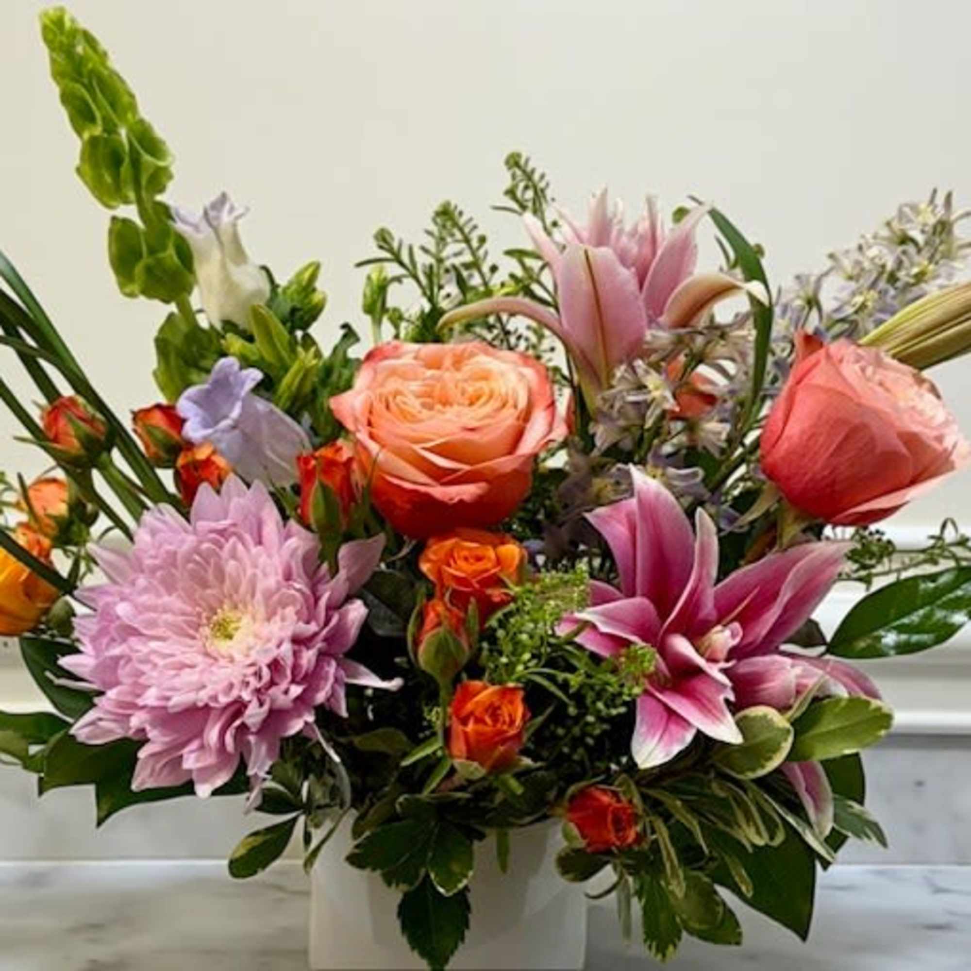 Mixed bouquet with pink lilies, roses, and chrysanthemums in a white vase