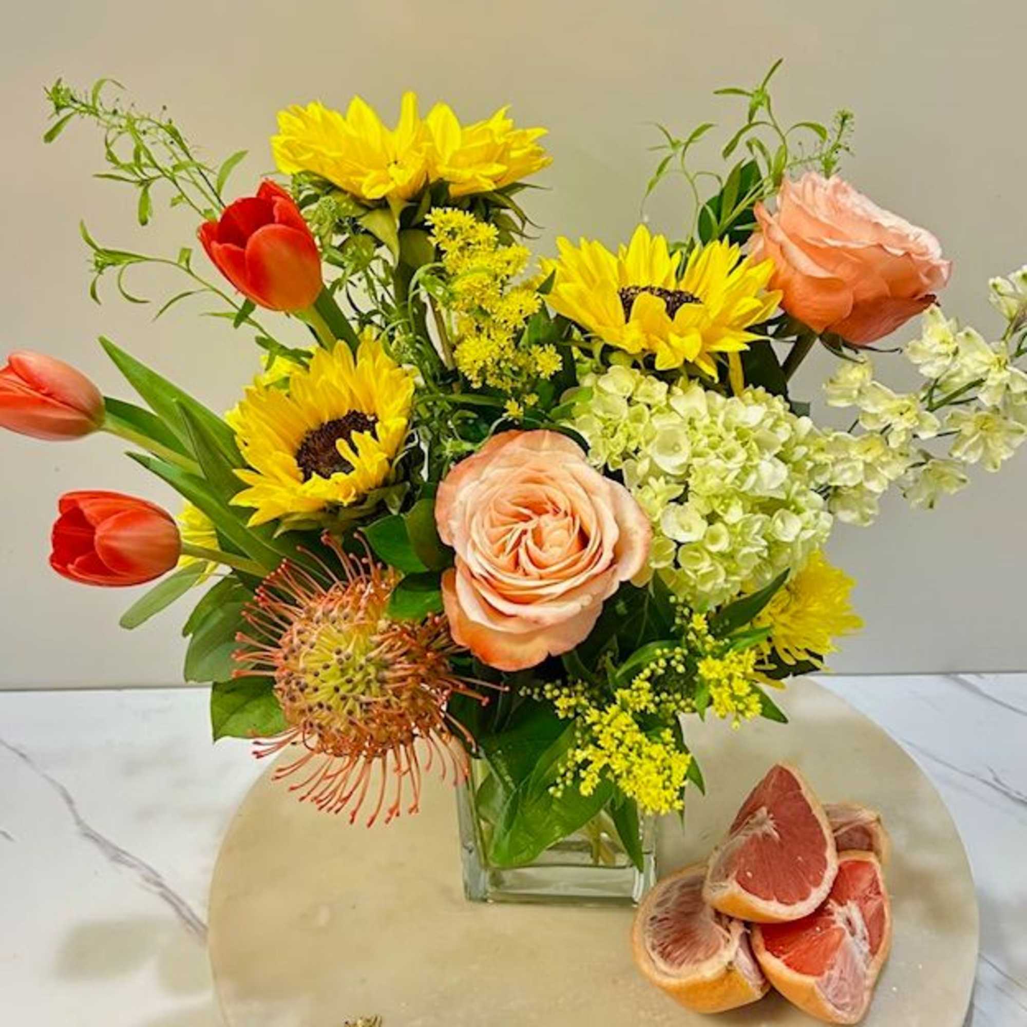 Mixed bouquet with sunflowers, tulips, roses, and hydrangeas in a glass vase