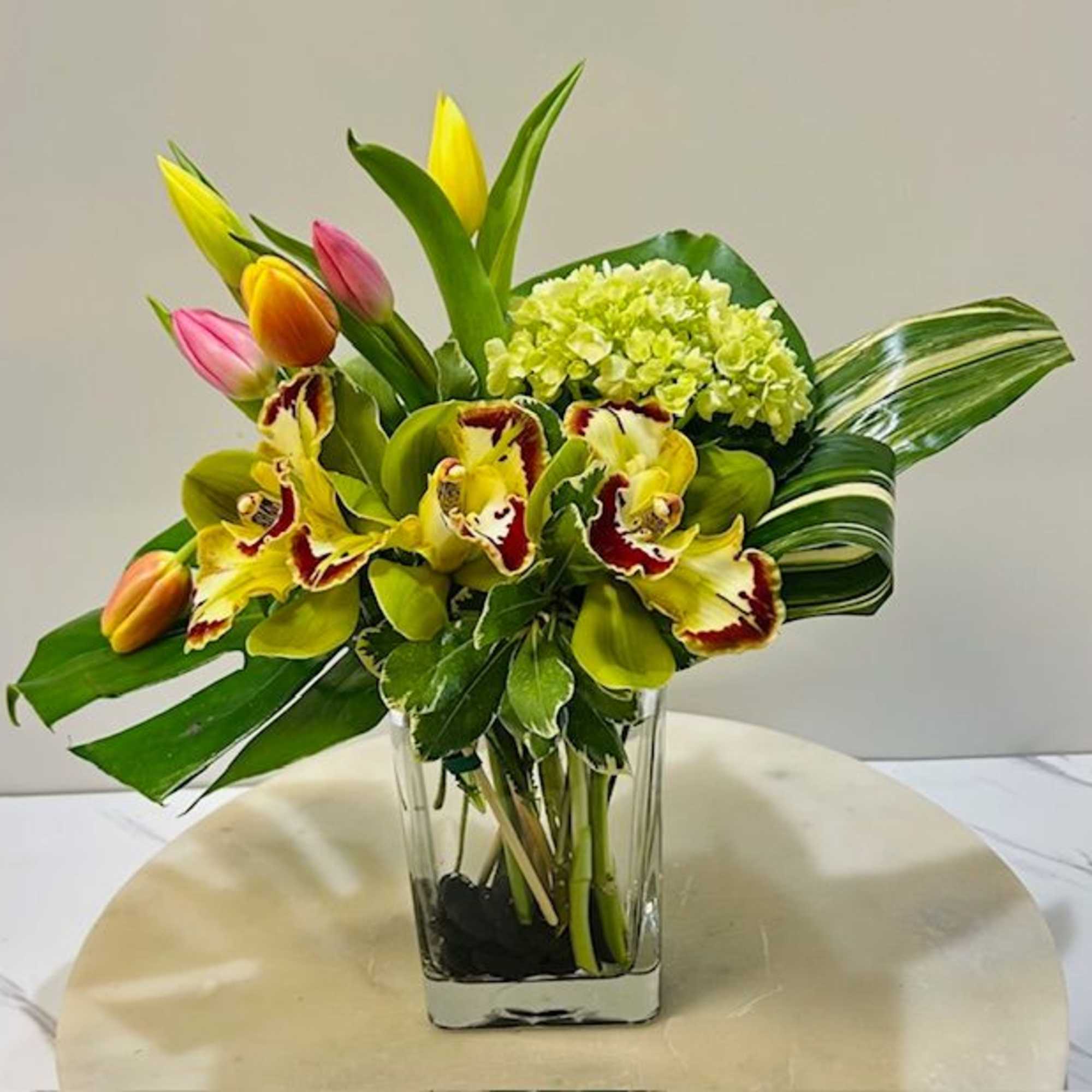 Tropical bouquet with tulips, orchids, and hydrangea in a clear vase