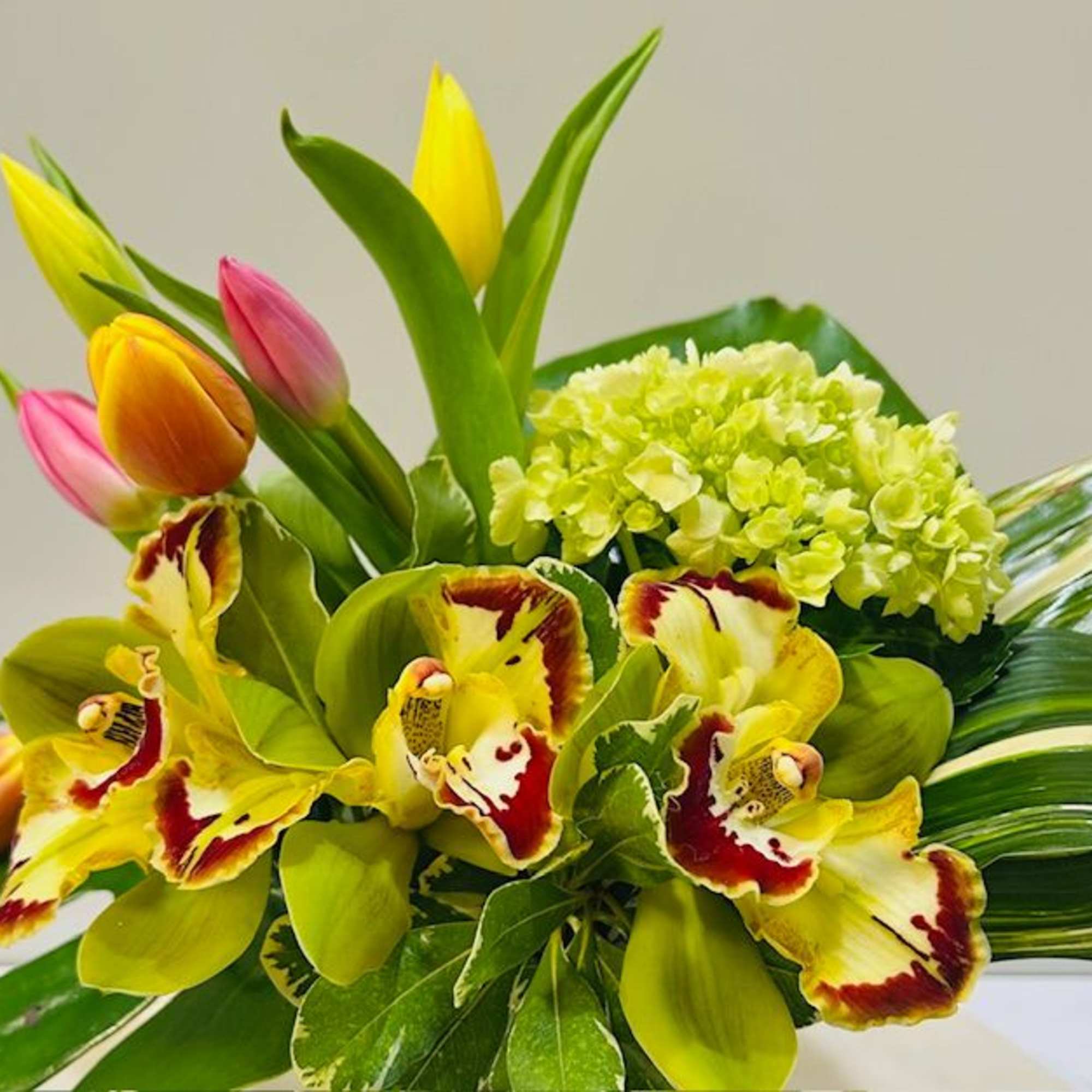 Bouquet of yellow and pink tulips with green orchids and hydrangea
