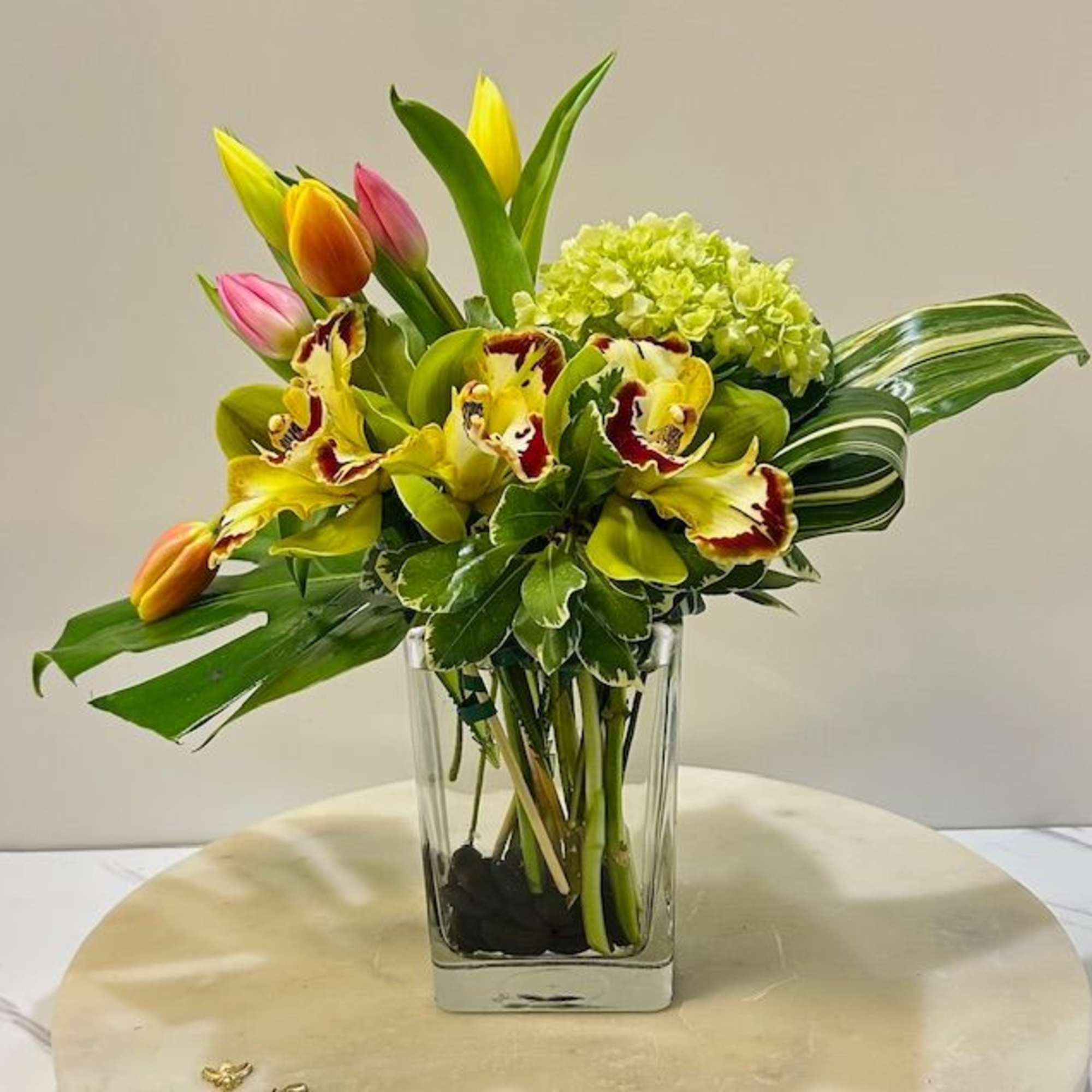 Bouquet of tulips and orchids in a clear glass vase