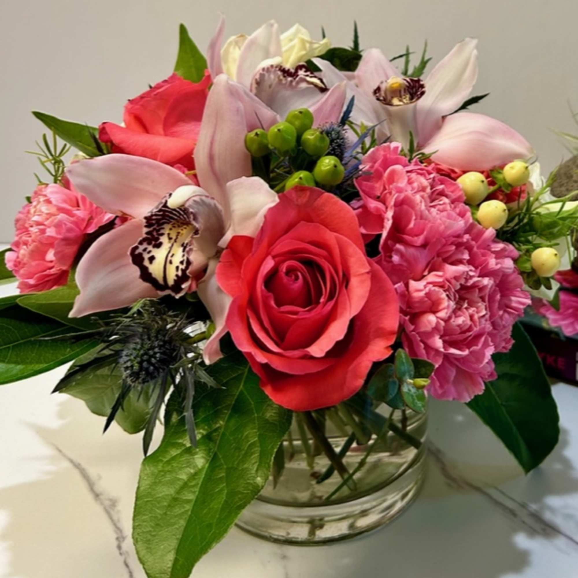 Bouquet of pink roses, orchids, and carnations in a glass vase