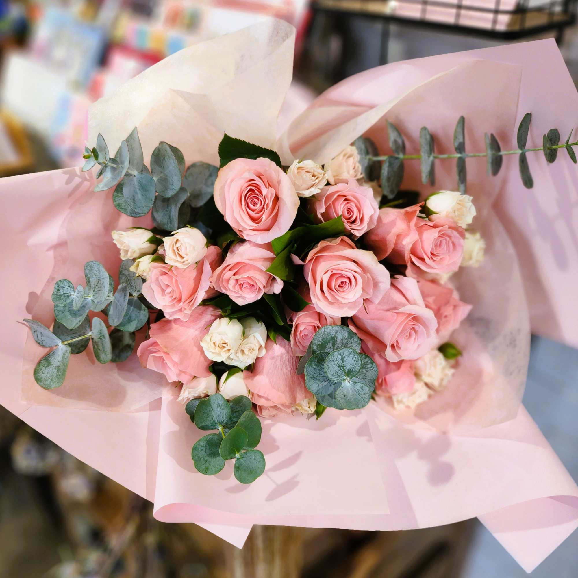 Pink rose bouquet wrapped in pale pink paper with eucalyptus