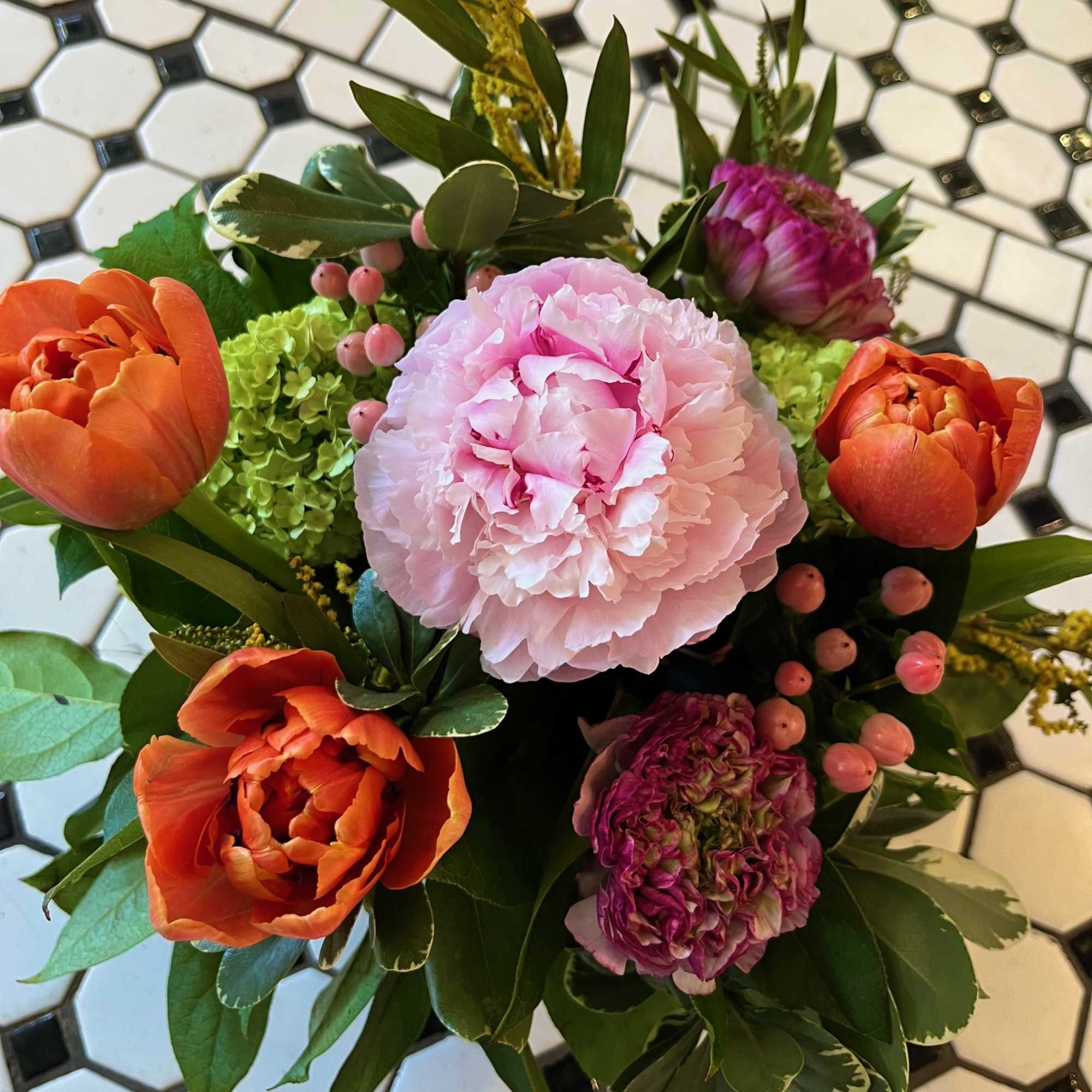 Bouquet of pink peonies and orange tulips with green hydrangea and berries