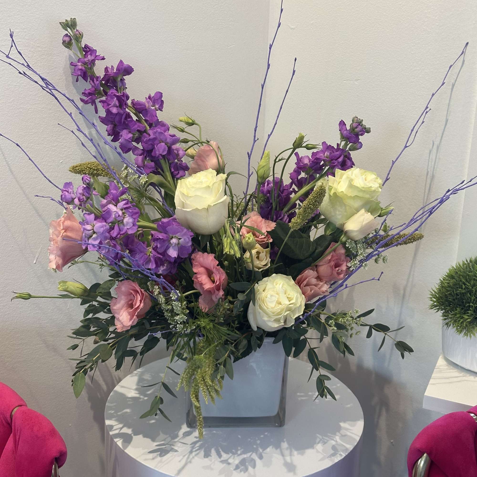 Purple and pink floral arrangement in a square vase with long branches
