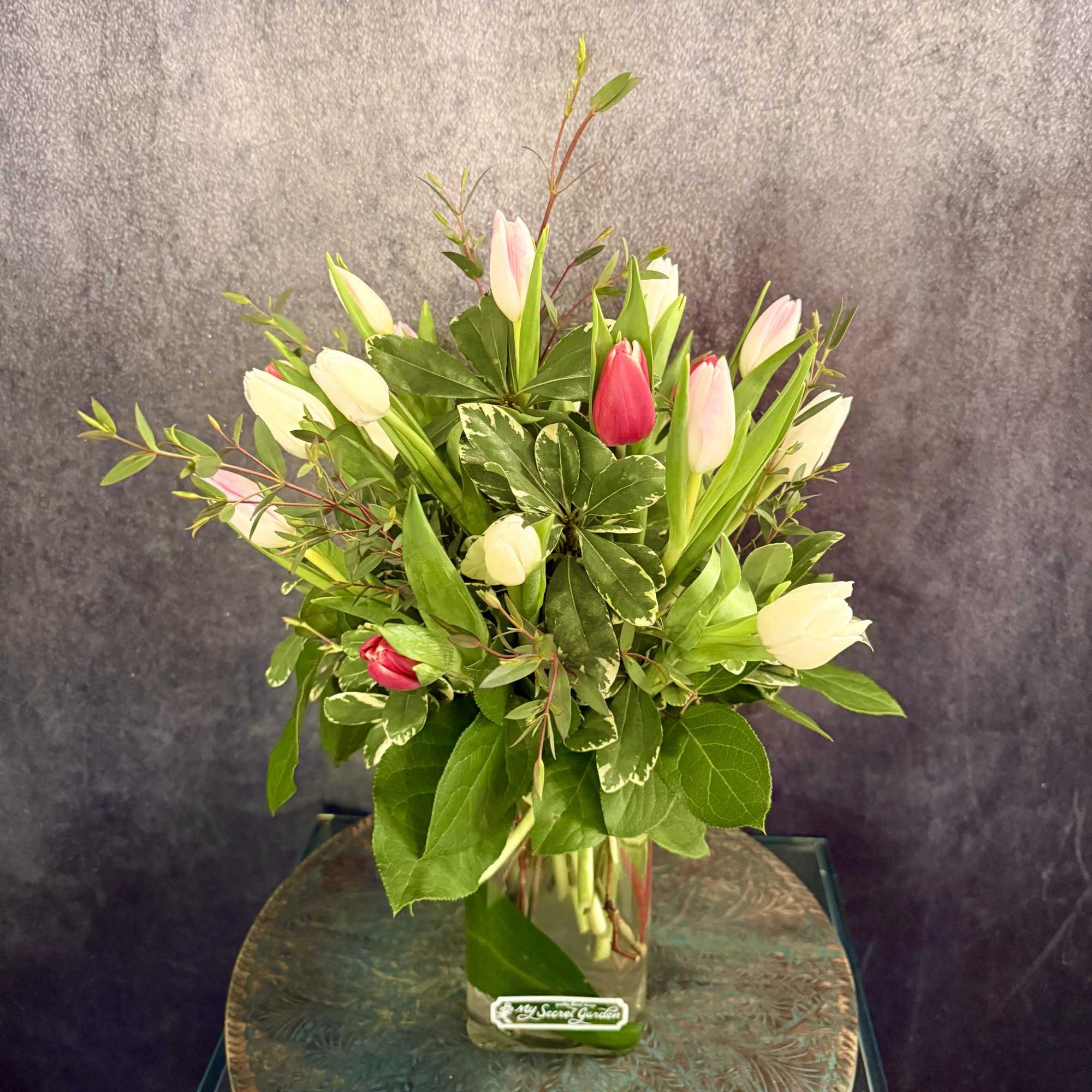 Pink and white tulips arranged in a clear glass vase