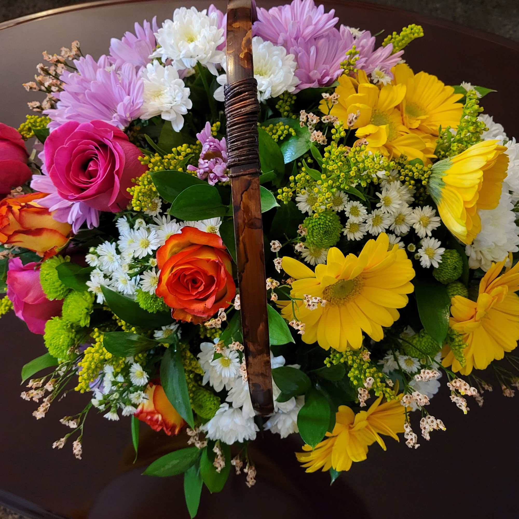 Mixed bouquet with roses and daisies in a basket handle arrangement