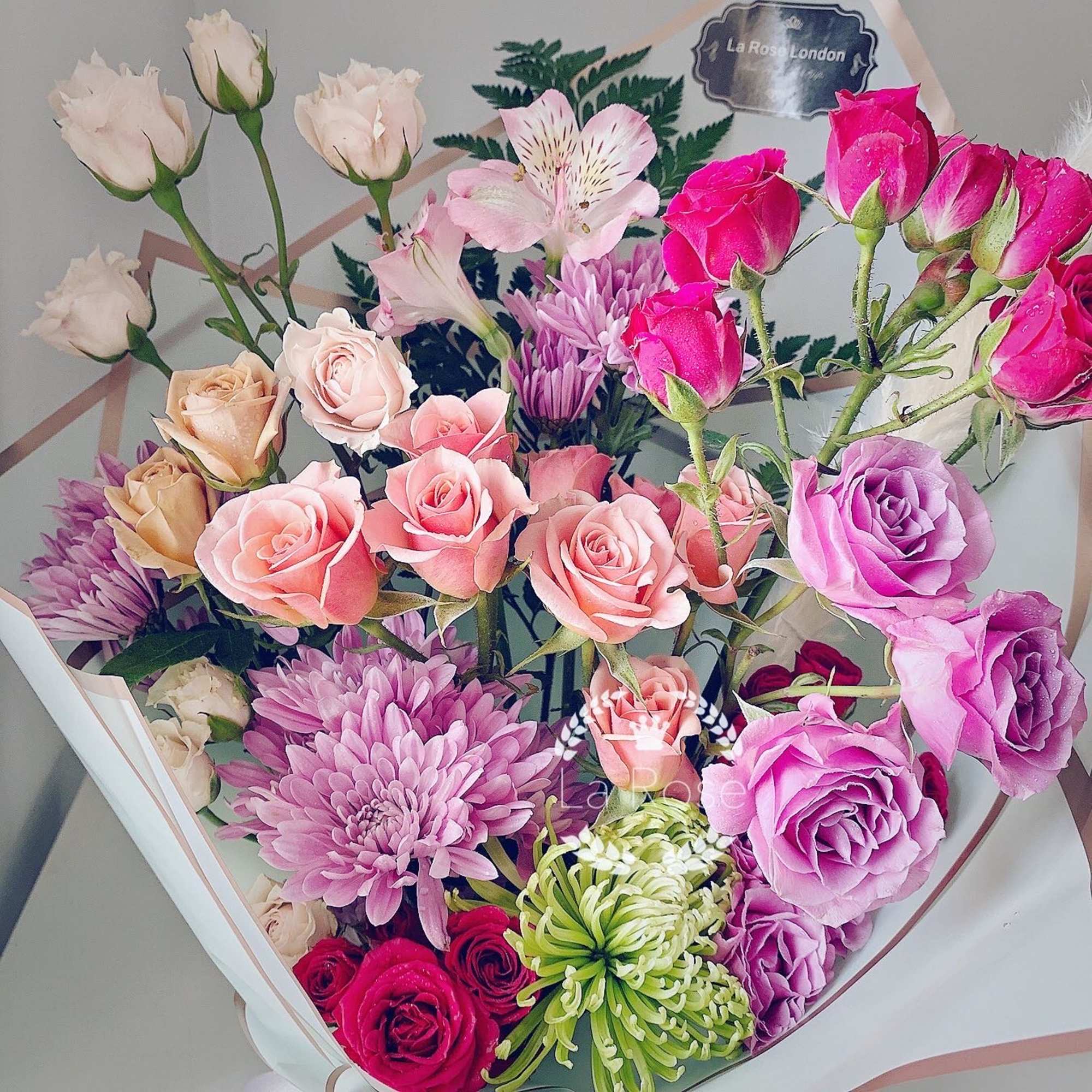 Mixed bouquet of pink, purple, and cream roses with chrysanthemums