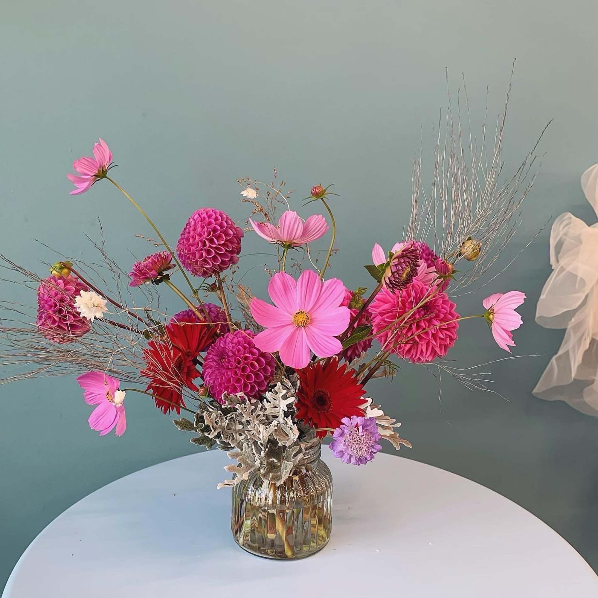 Pink and red mixed flower arrangement in a ribbed glass vase