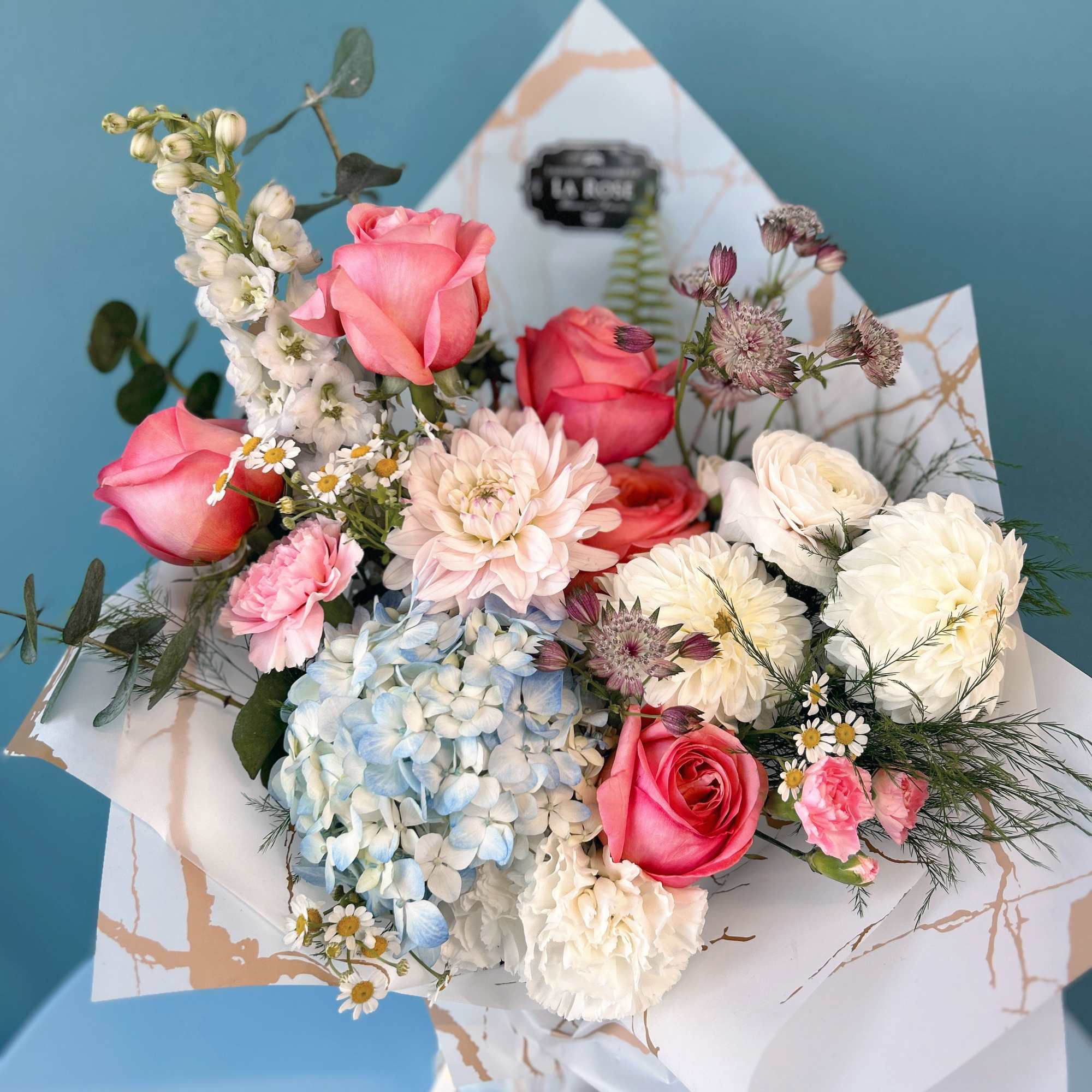 Bouquet of pink roses, hydrangea, and white blooms in decorative wrap