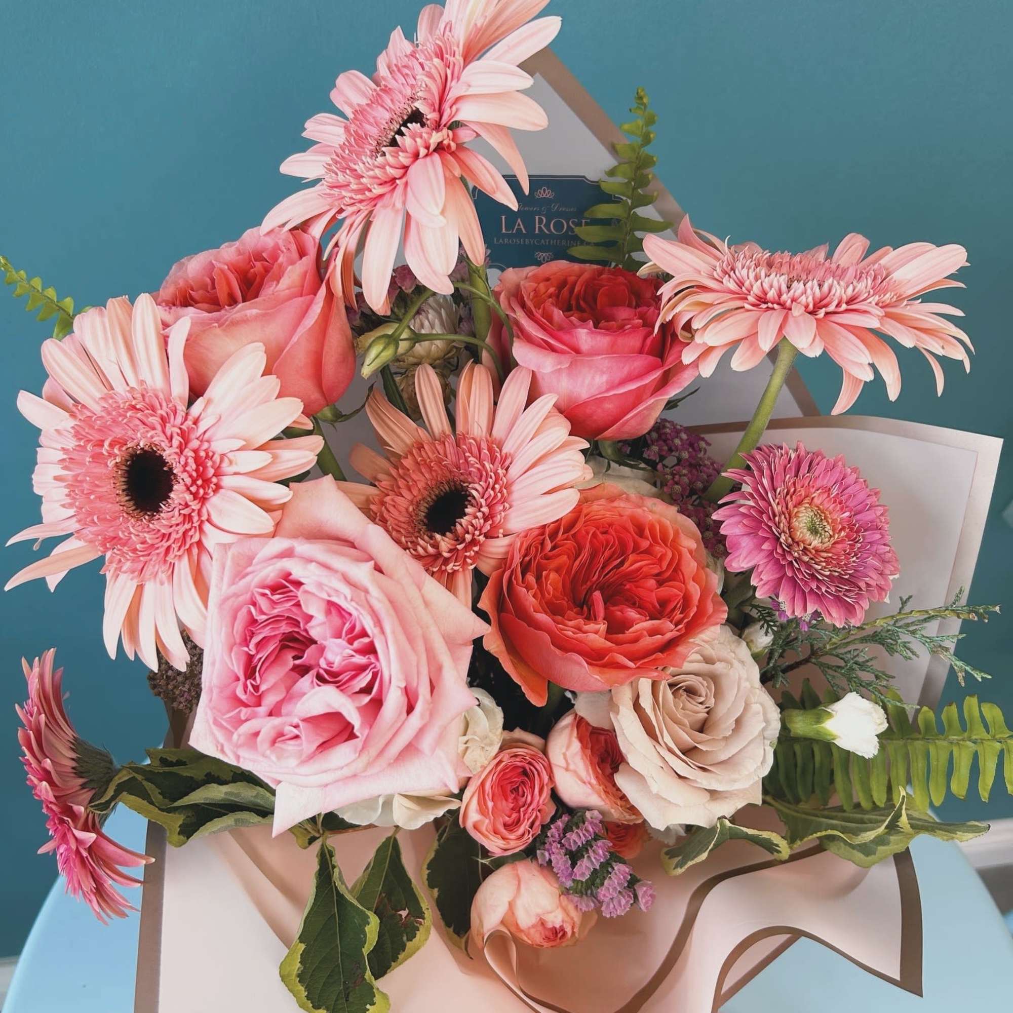 Pink and coral bouquet with gerbera daisies and roses in paper wrap