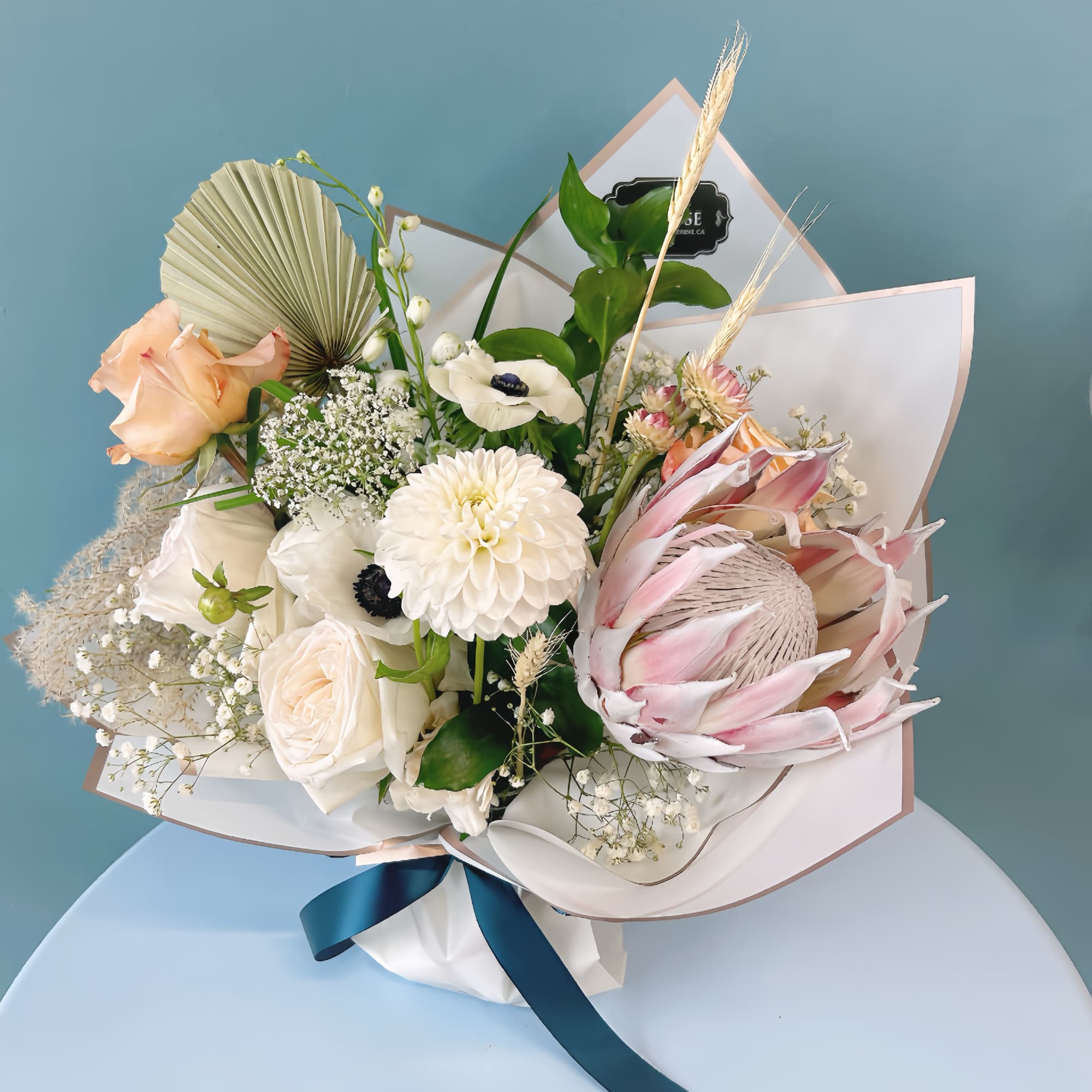 Bouquet of white and blush flowers with a blue ribbon wrap