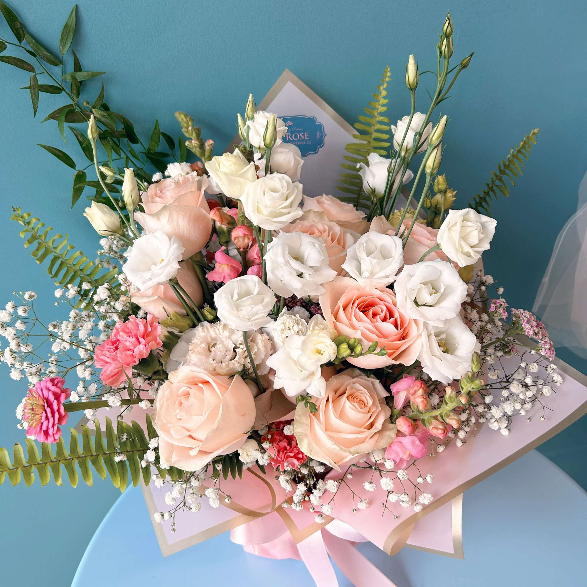 Bouquet of blush and white roses with pink accents and ribbon wrap