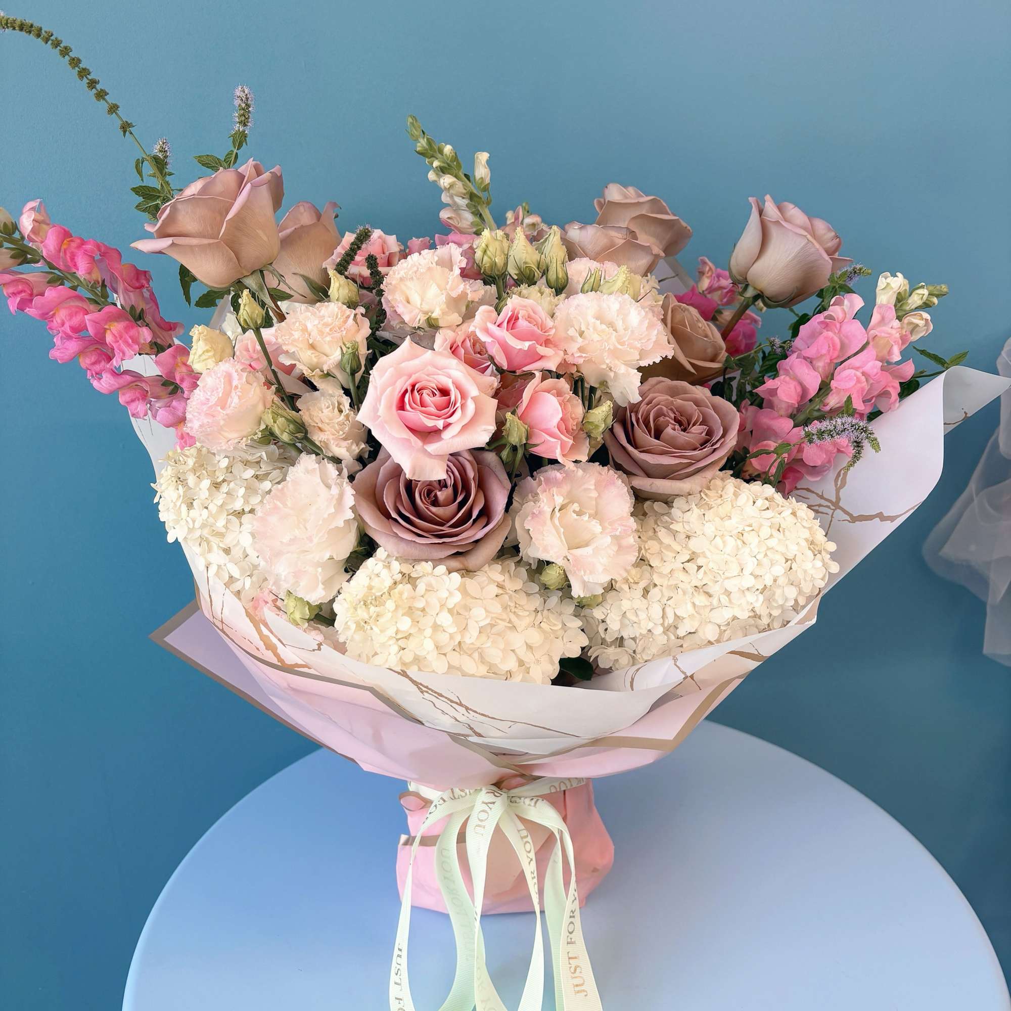 Bouquet of pink and taupe roses with pale hydrangeas and snapdragons