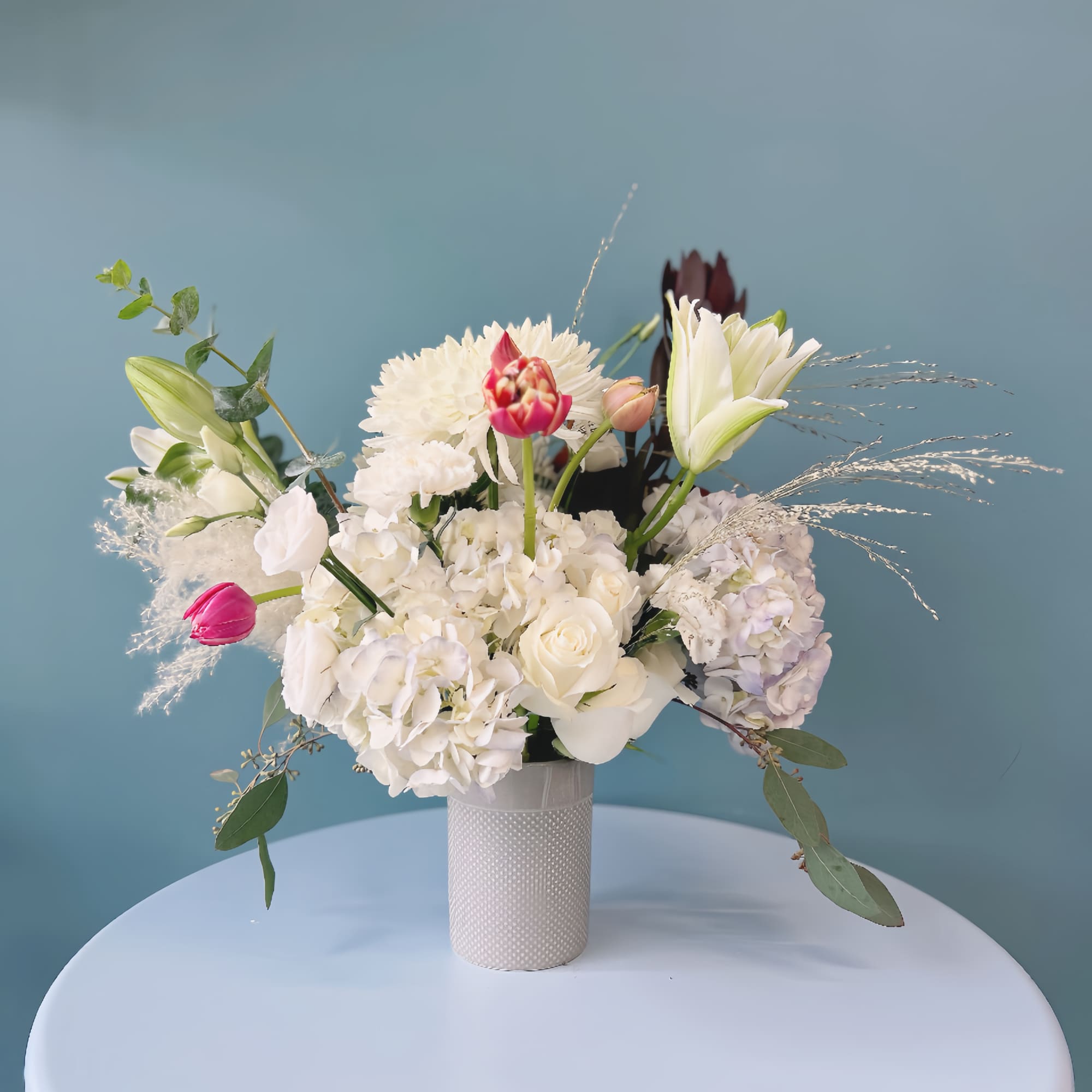 White floral arrangement in a textured vase with pink accents