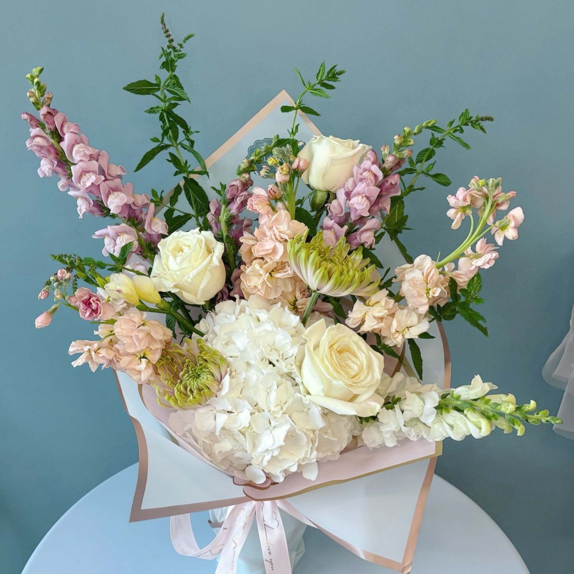 Pastel bouquet of white roses, hydrangea, and pink snapdragons