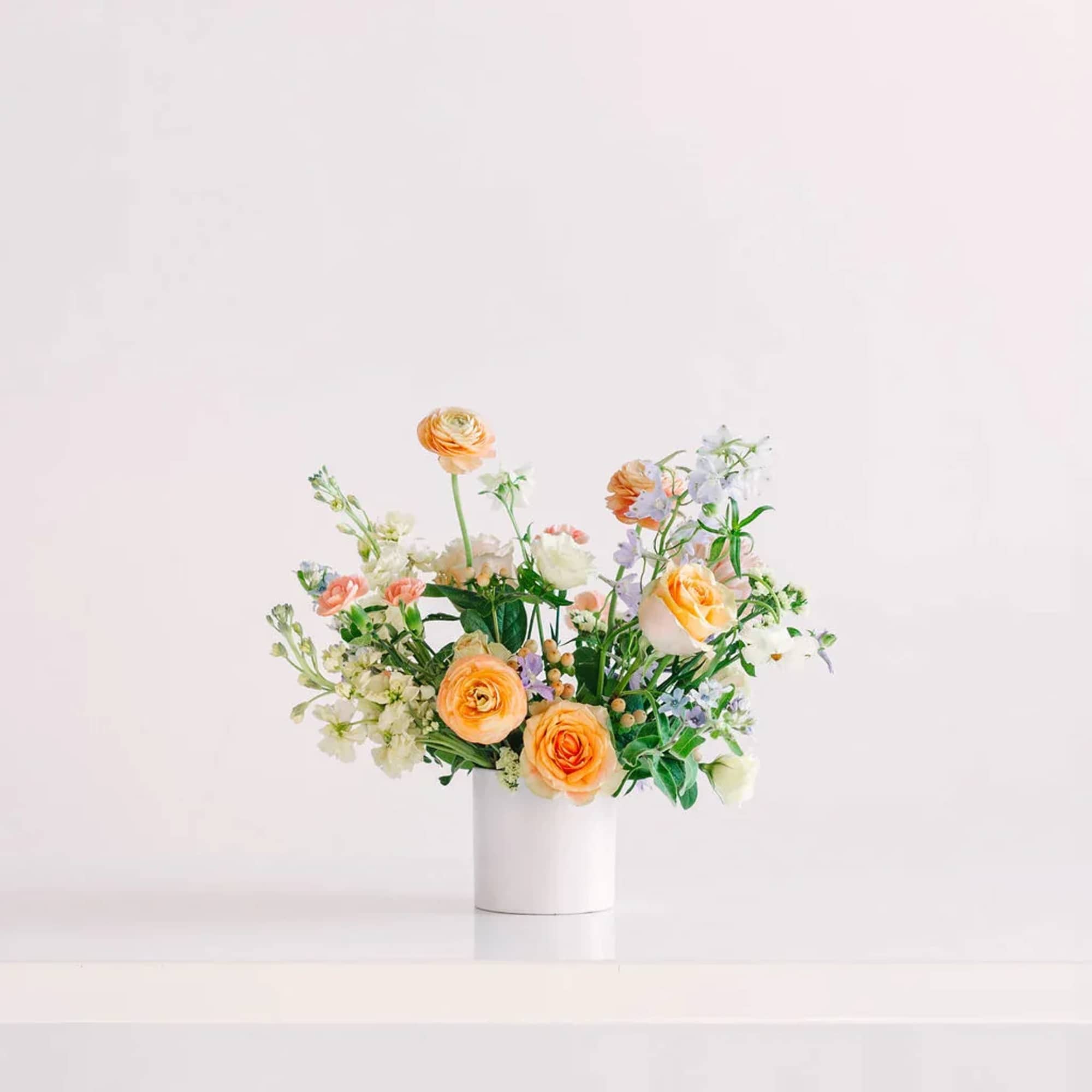 Orange and white mixed flower arrangement in a white vase