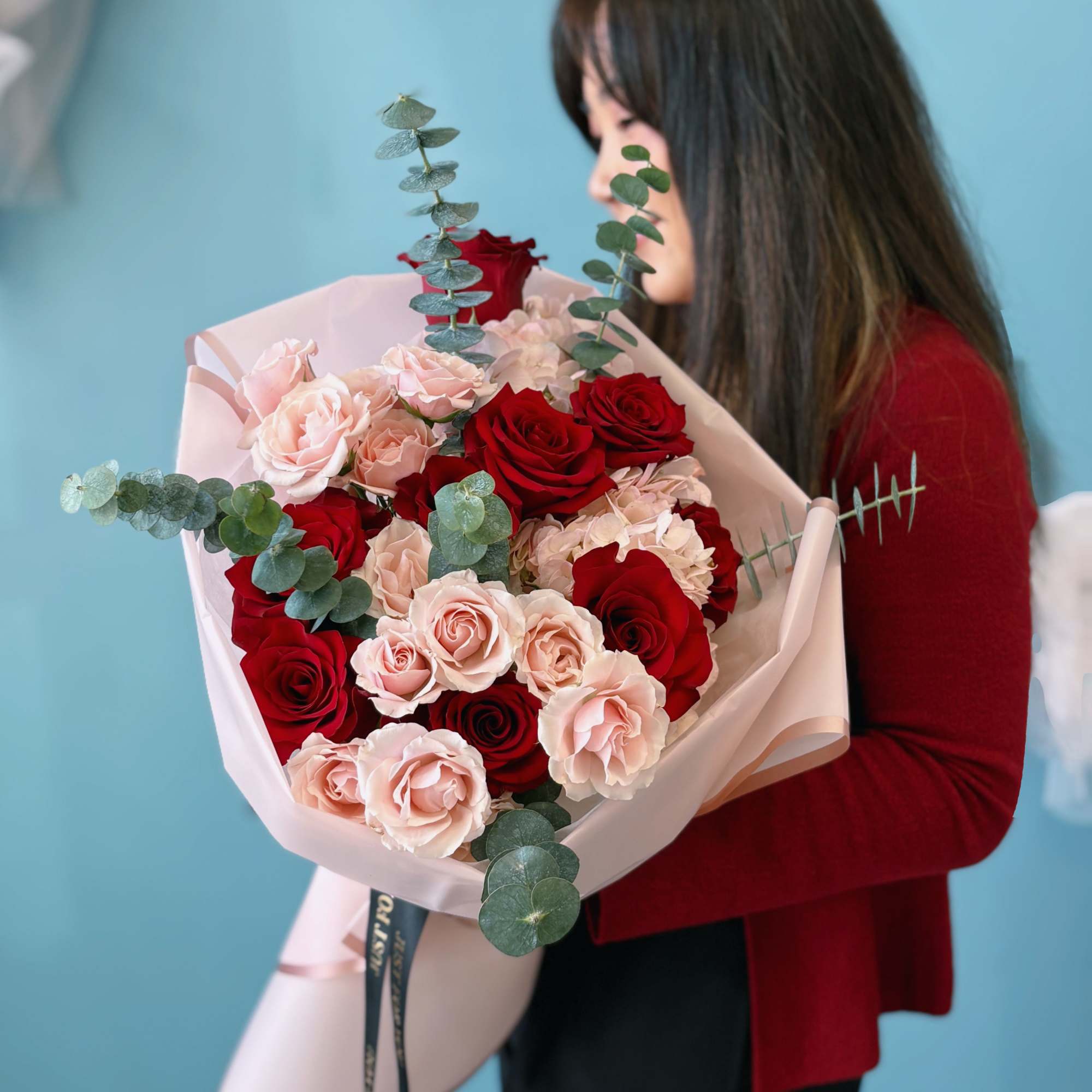 Bouquet of red and blush roses wrapped in pale pink paper