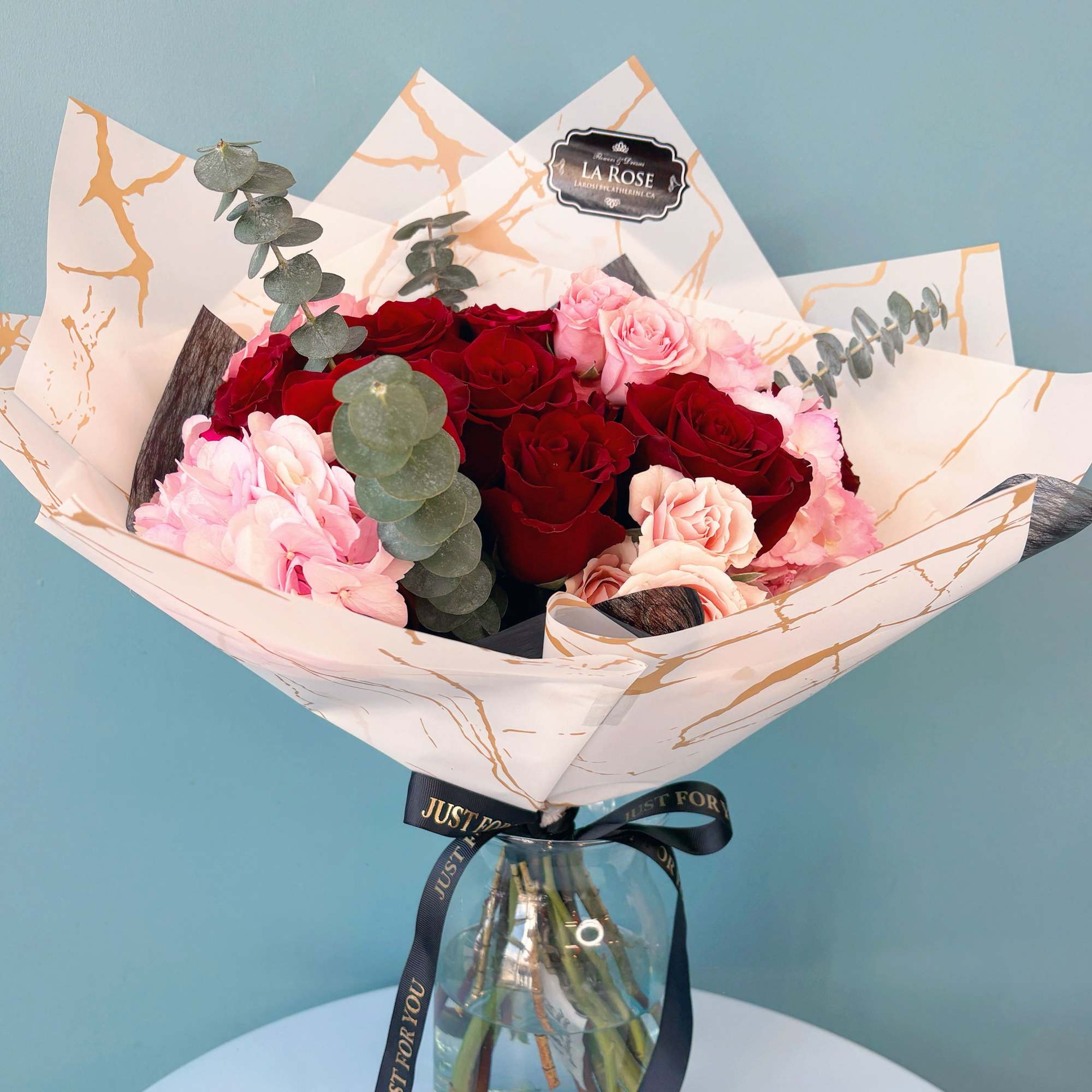 Bouquet of red and pink roses in a glass vase with a ribbon