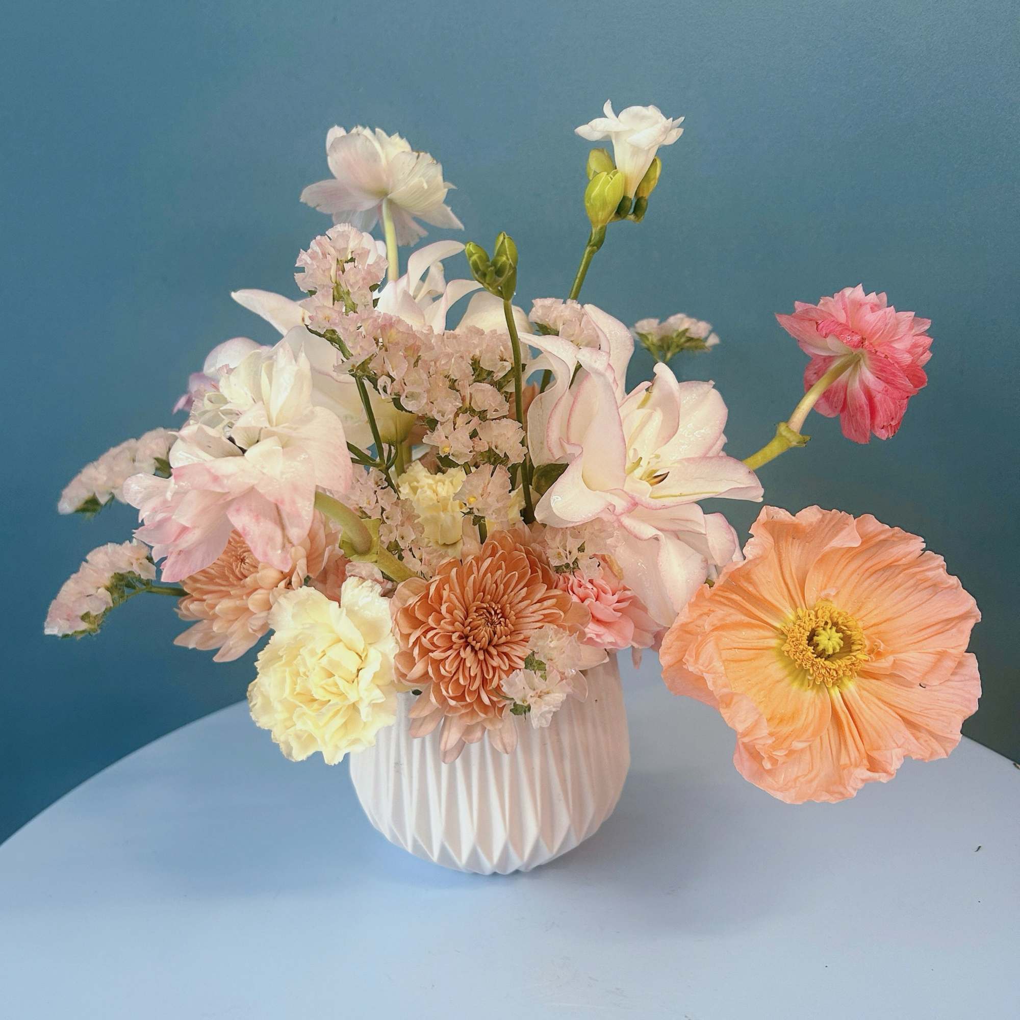 Pastel mixed flower arrangement in a white vase