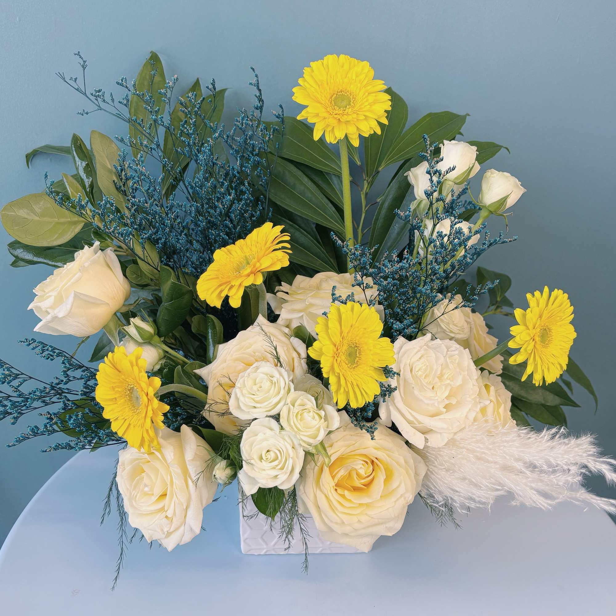 Bouquet of white roses and yellow gerbera daisies in a white container